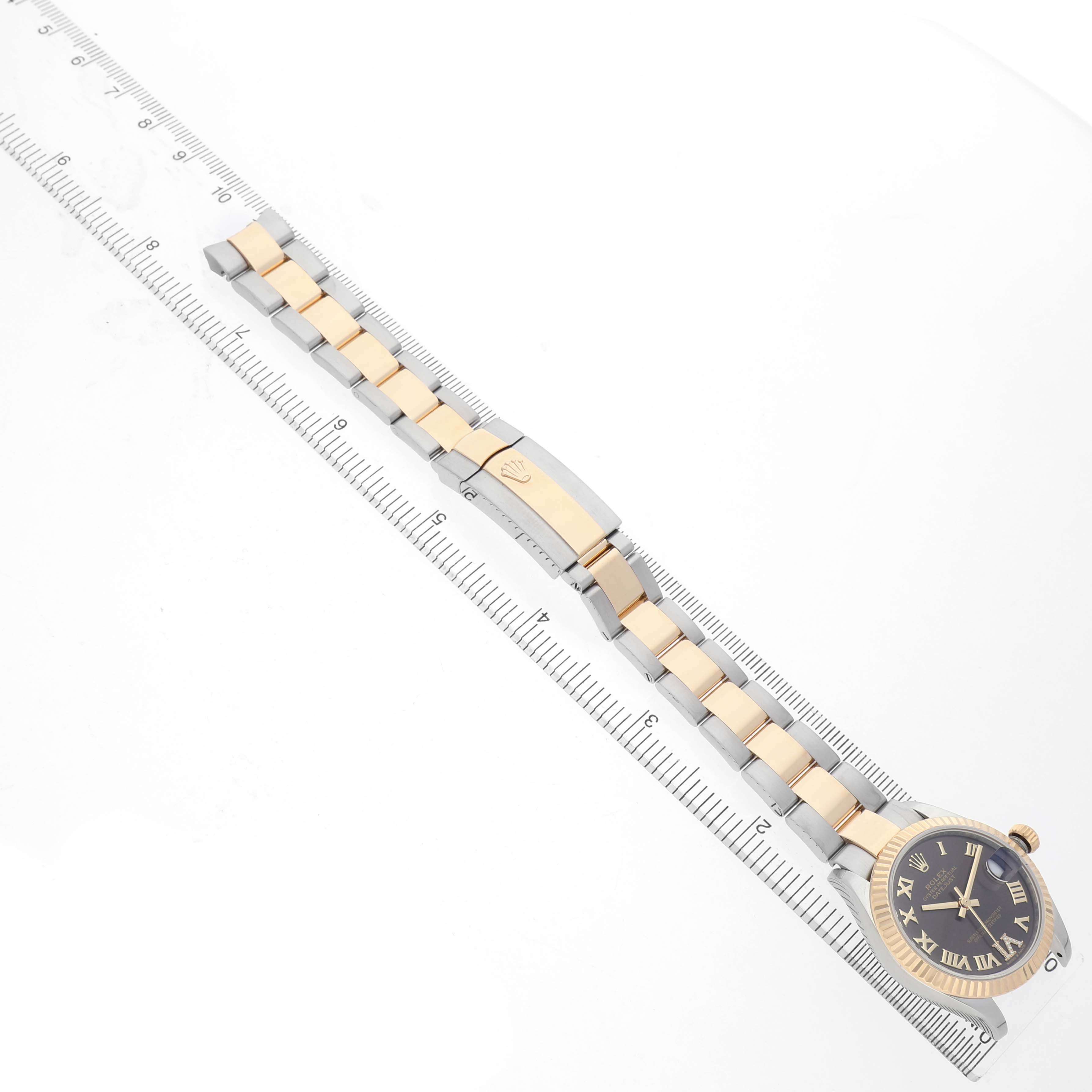 The Rolex Mid-Size 278273 Women's Steel and Gold (two tone) Brown Dial watch is shown from a top-down angle, highlighting the face, bracelet, and clasp alongside a ruler.
