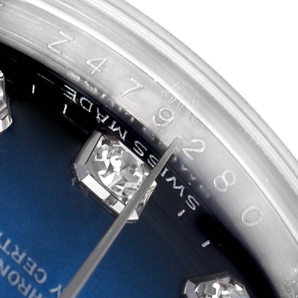 The image shows a close-up angle of a Rolex Datejust 179174 Women's Stainless Steel Blue Dial 179174 Women's Stainless Steel Blue Dial watch, focusing on part of the sapphire crystal, bezel with engraved numbers, and a portion of the dial with a diamond marker.