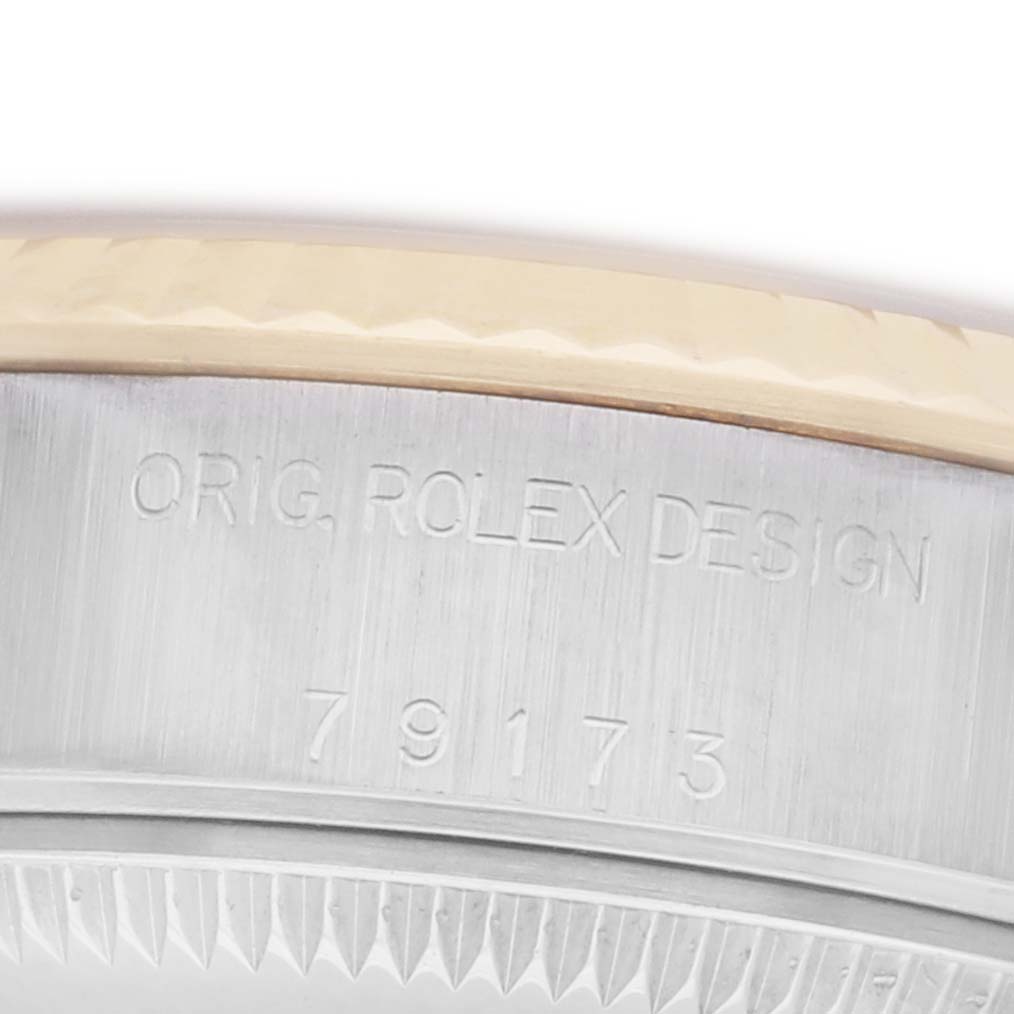 The image shows the side of a Rolex Datejust 79173 Women
s Steel and Gold (two tone) Champagne Dial 79173 Women
s Steel and Gold (two tone) Champagne Dial watch, featuring engraved branding and model number on the case edge.