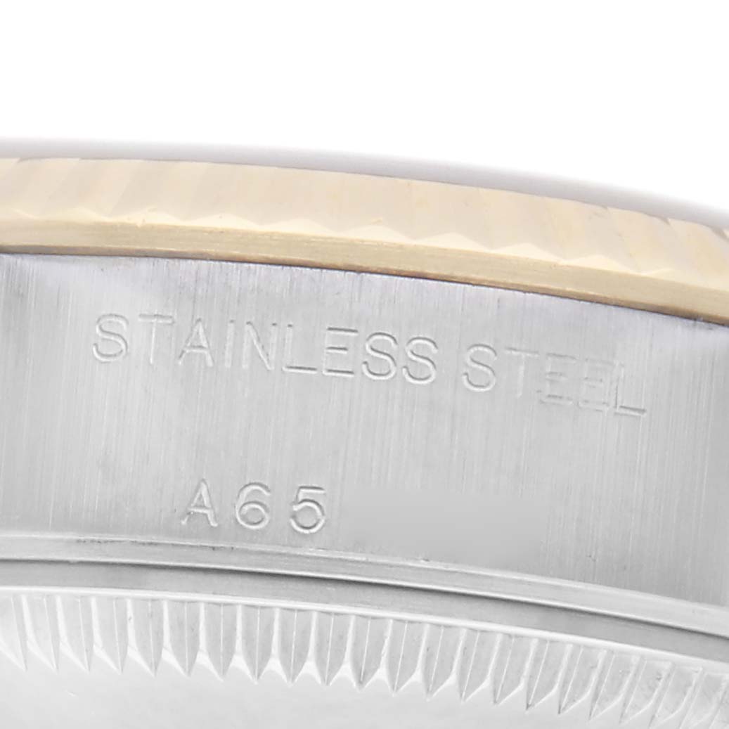 The image shows a side angle of the Rolex Datejust 79173 Women
s Steel and Gold (two tone) Champagne Dial 79173 Women
s Steel and Gold (two tone) Champagne Dial watch, focusing on the stainless steel case with engraved text.