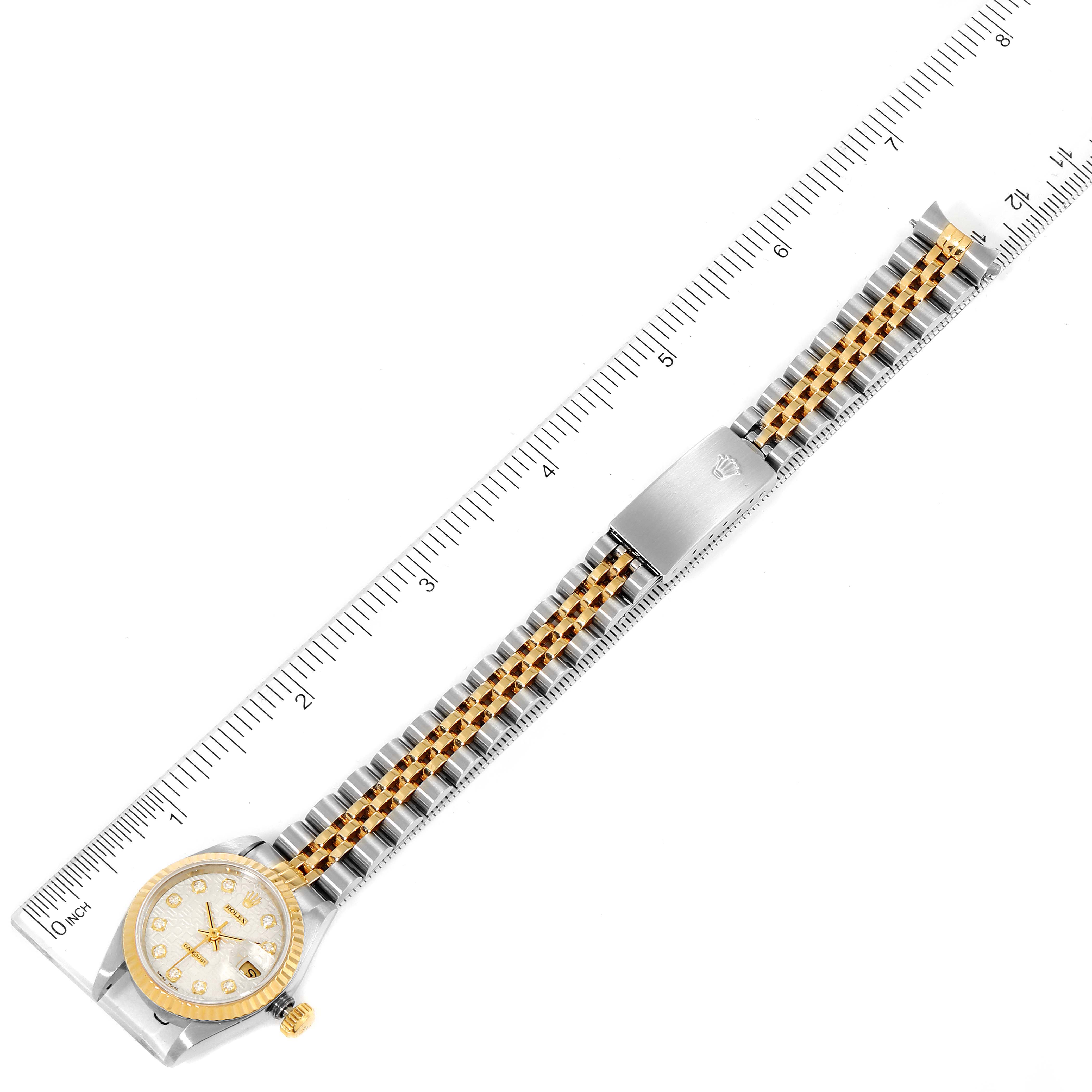 This image shows a Rolex Datejust 79173 Women's Steel and Gold (two tone) Silver Dial 79173 Women's Steel and Gold (two tone) Silver Dial watch laid flat with a measuring tape for scale, highlighting the watch face, band, and clasp.
