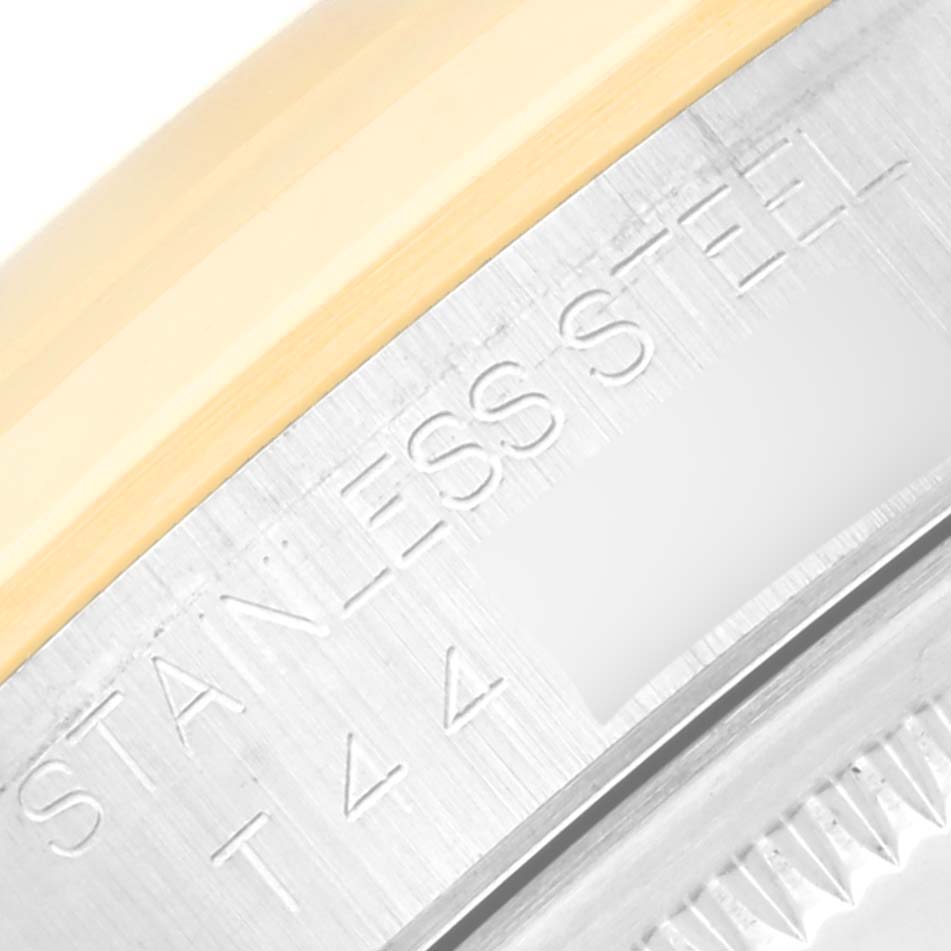 This close-up image of the Rolex Datejust 16203 Men
s Steel and Gold (two tone) White Dial 16203 Men
s Steel and Gold (two tone) White Dial watch shows part of the stainless steel case and the edge of the bezel.