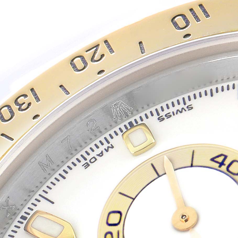 The image shows a close-up of the Rolex Daytona 116523 Men
s Steel and Gold (two tone) White Dial 116523 Men
s Steel and Gold (two tone) White Dial
s bezel, dial, and hand, focusing on the 130-110 numerical markers.