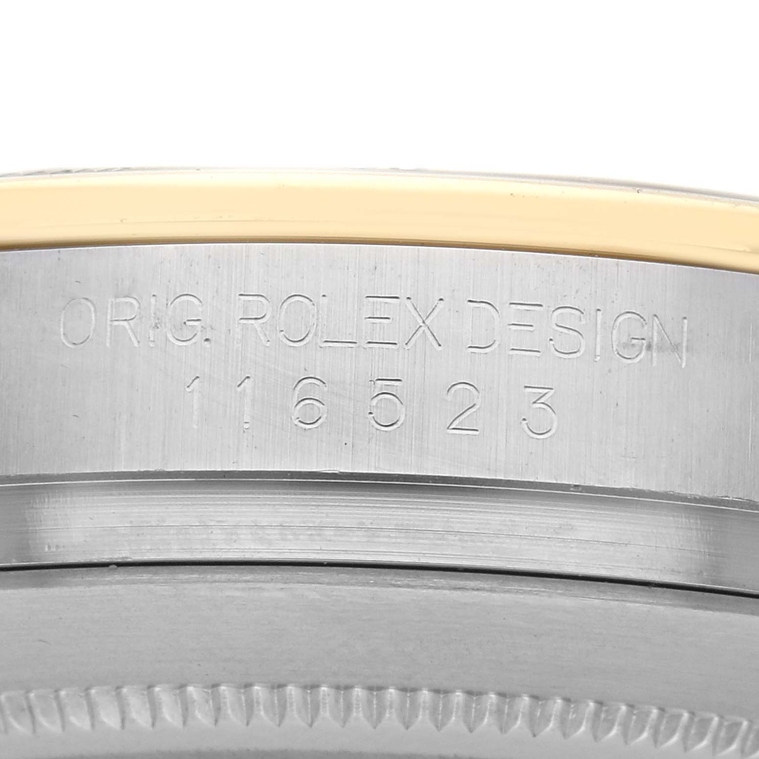 The image shows the side view of a Rolex Daytona 116523 Men
s Steel and Gold (two tone) White Dial 116523 Men
s Steel and Gold (two tone) White Dial, highlighting its engraved bezel with the design and model number.