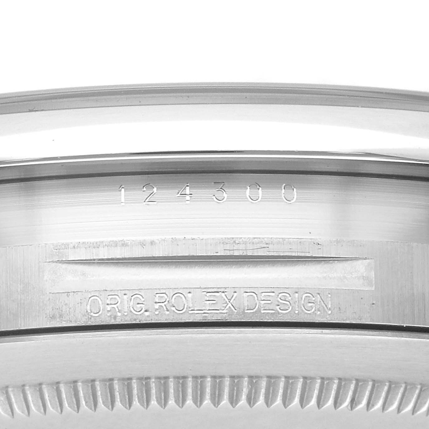 The image shows a close-up of the side of a Rolex Oyster Perpetual 124300 Men
s Stainless Steel Black Dial 124300 Men
s Stainless Steel Black Dial watch case with engraved serial number and "ORIG. ROLEX DESIGN."