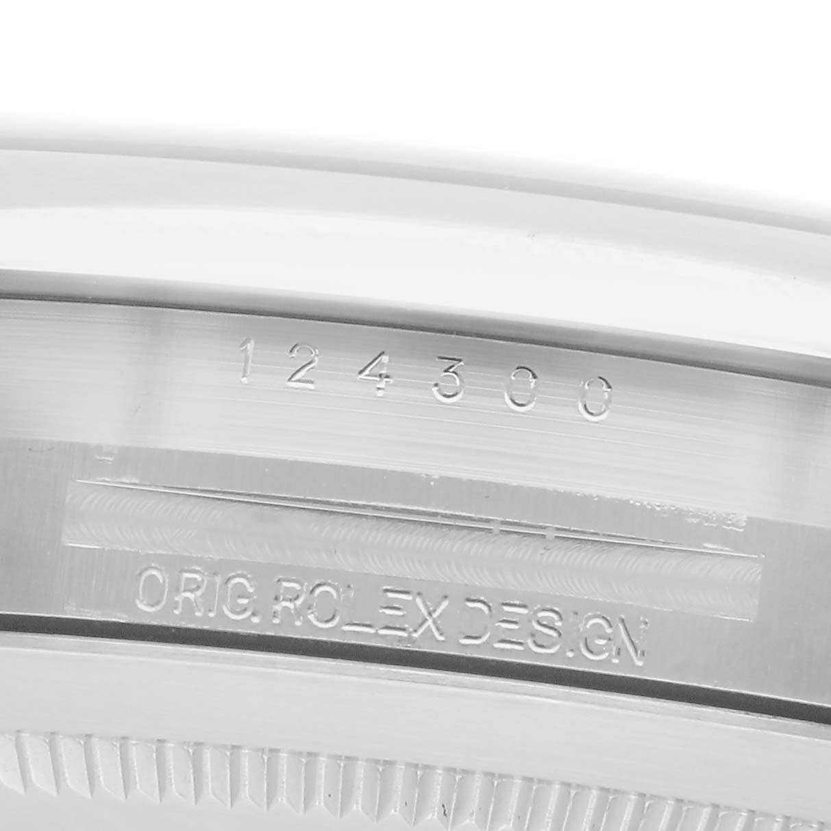 The image shows a close-up of the side of a Rolex Oyster Perpetual 124300 Men
s Stainless Steel Silver Dial 124300 Men
s Stainless Steel Silver Dial watch with engravings of the model number and "ORIG. ROLEX DESIGN."
