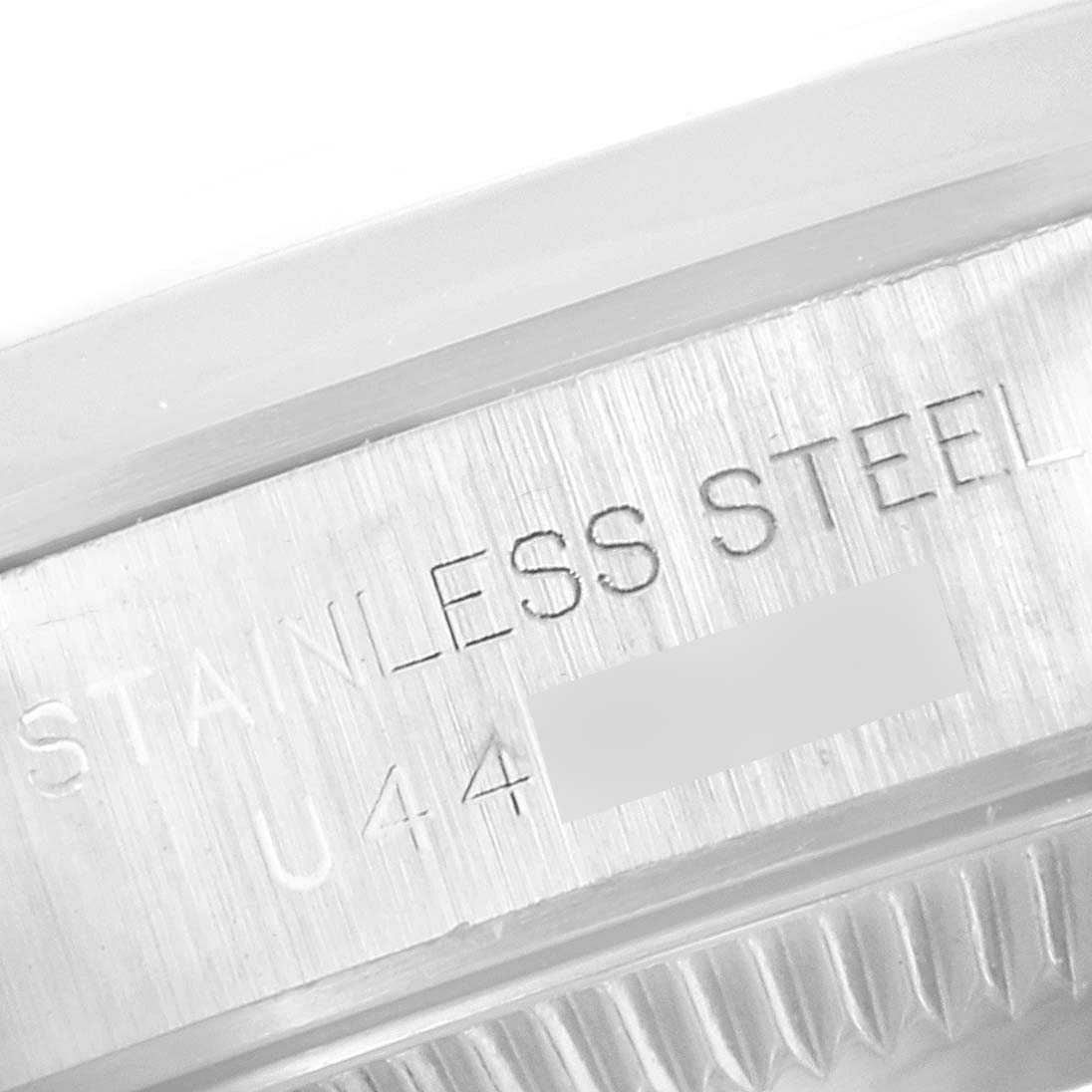 This image shows an engraved section of the stainless steel casing on a Rolex Oyster Perpetual 67180 Women's Stainless Steel Blue Dial 67180 Women's Stainless Steel Blue Dial watch.