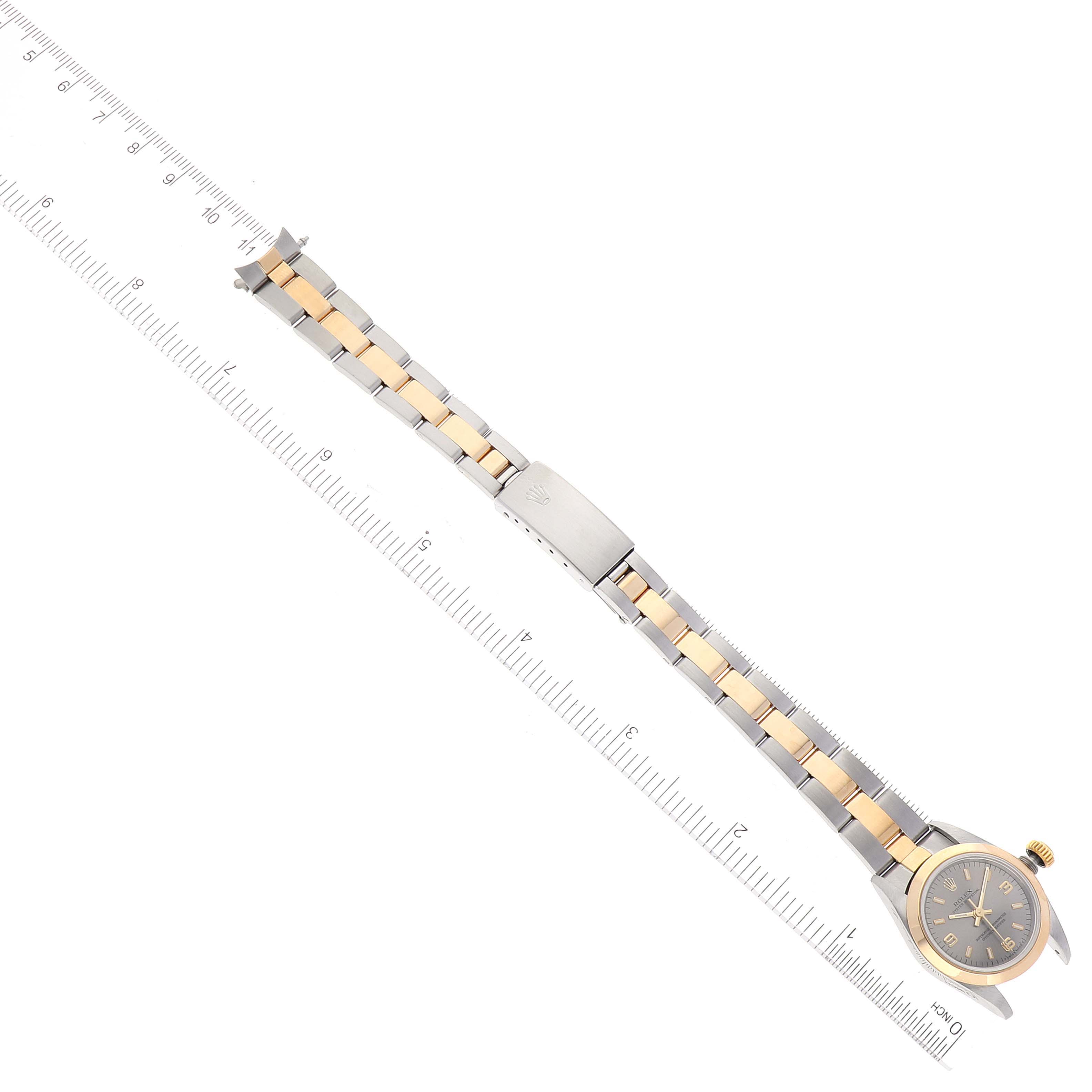 The image shows a Rolex Oyster Perpetual 67183 Women's Steel and Gold (two tone) Grey Dial 67183 Women's Steel and Gold (two tone) Grey Dial watch with a two-tone metal band, laid flat alongside a ruler.