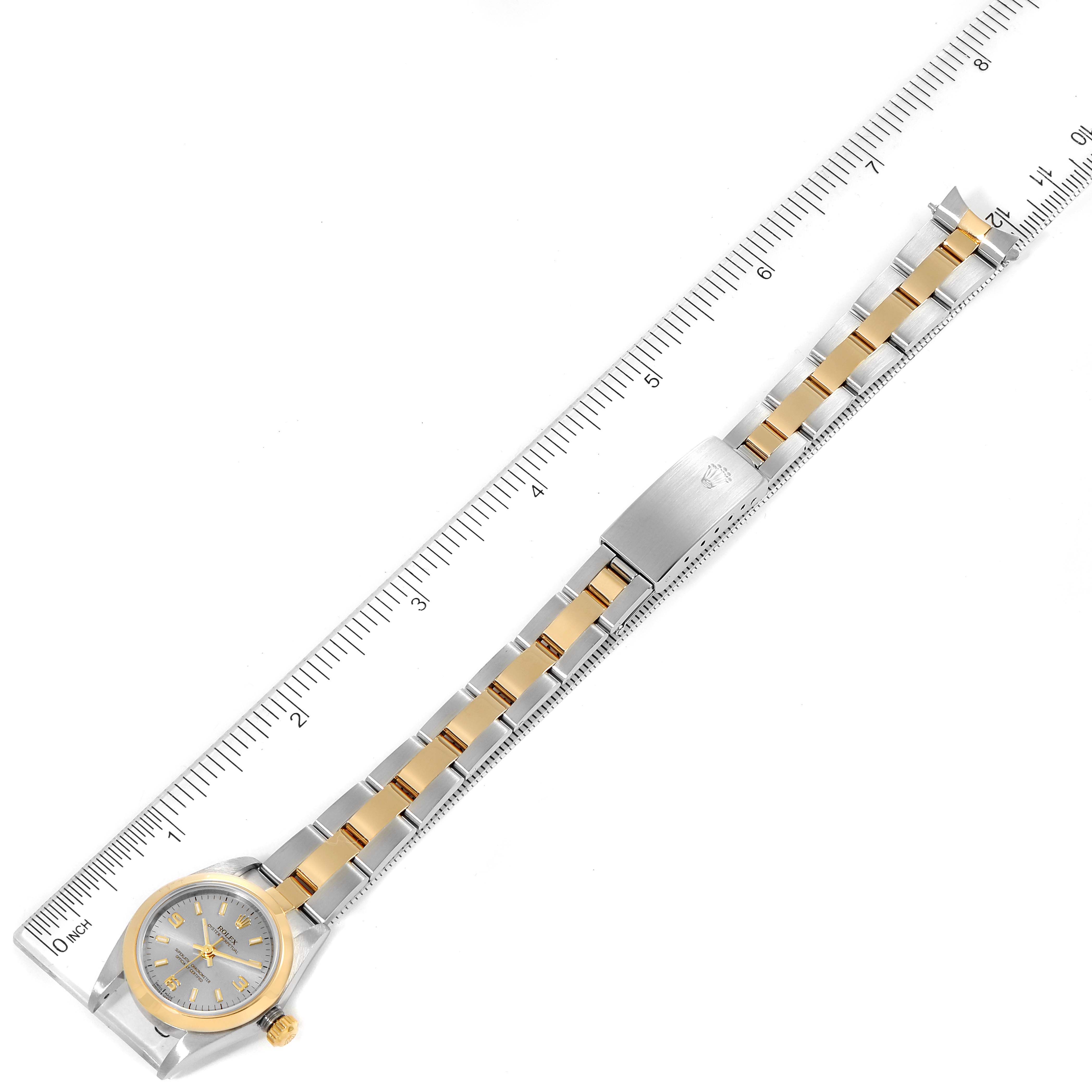 The image shows an Oyster Perpetual Rolex watch with a two-tone metal strap, displayed alongside a ruler for measurement.
