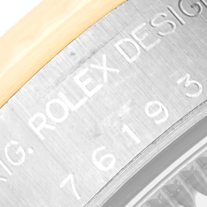 This close-up image shows part of the engraved bezel and the edge of the dial of a Rolex Oyster Perpetual 76193 Women's Steel and Gold (two tone) White Dial 76193 Women's Steel and Gold (two tone) White Dial watch.