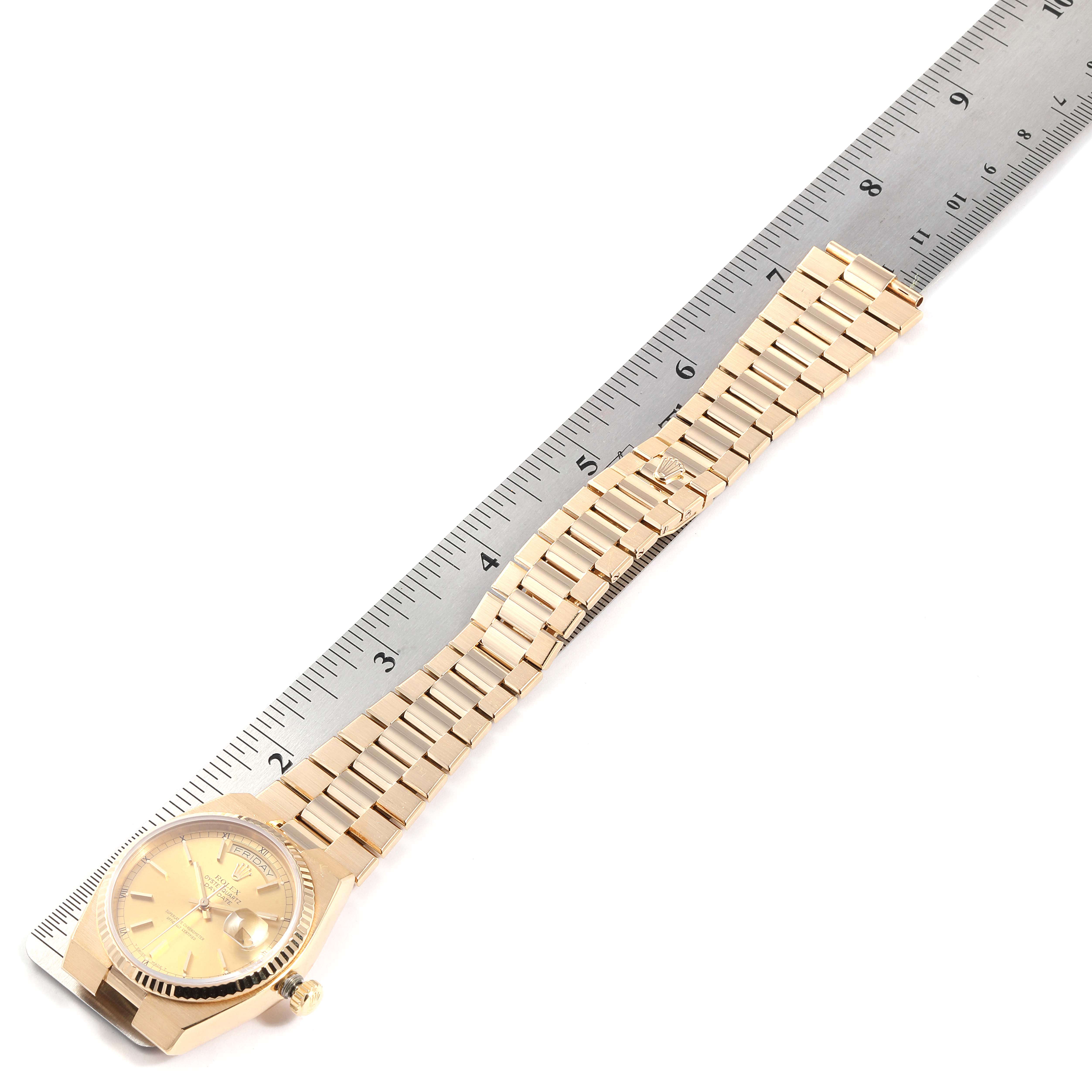 The image shows a gold Rolex Oysterquartz 19018 Men
s Yellow Gold Champagne Dial 19018 Men
s Yellow Gold Champagne Dial watch laid flat next to a ruler, displaying its bracelet and dial from an overhead angle.