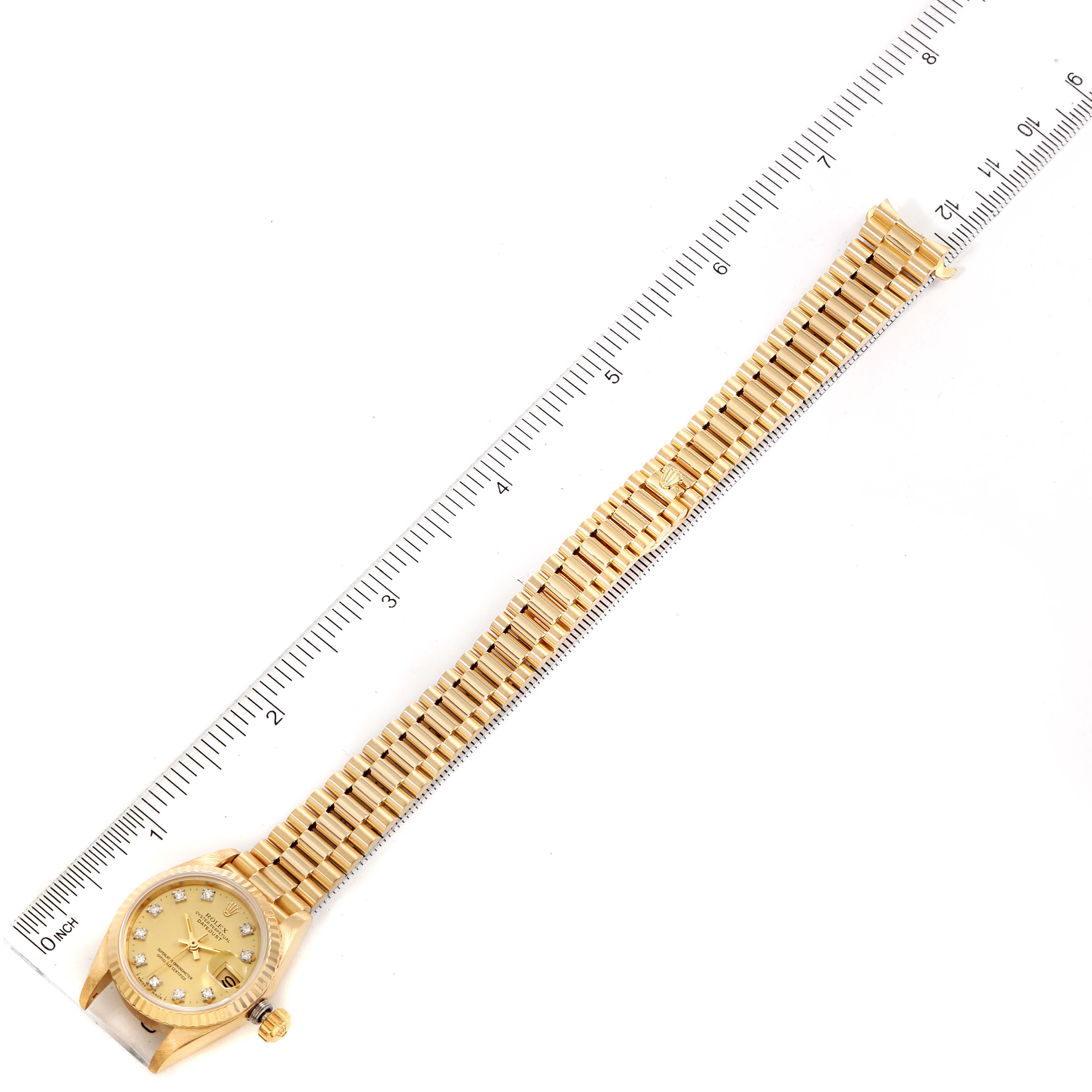 The image shows a top-down view of a Rolex President 69178 Women's Yellow Gold Champagne Dial 69178 Women's Yellow Gold Champagne Dial model watch, including the dial, bezel, crown, and bracelet, next to a ruler.
