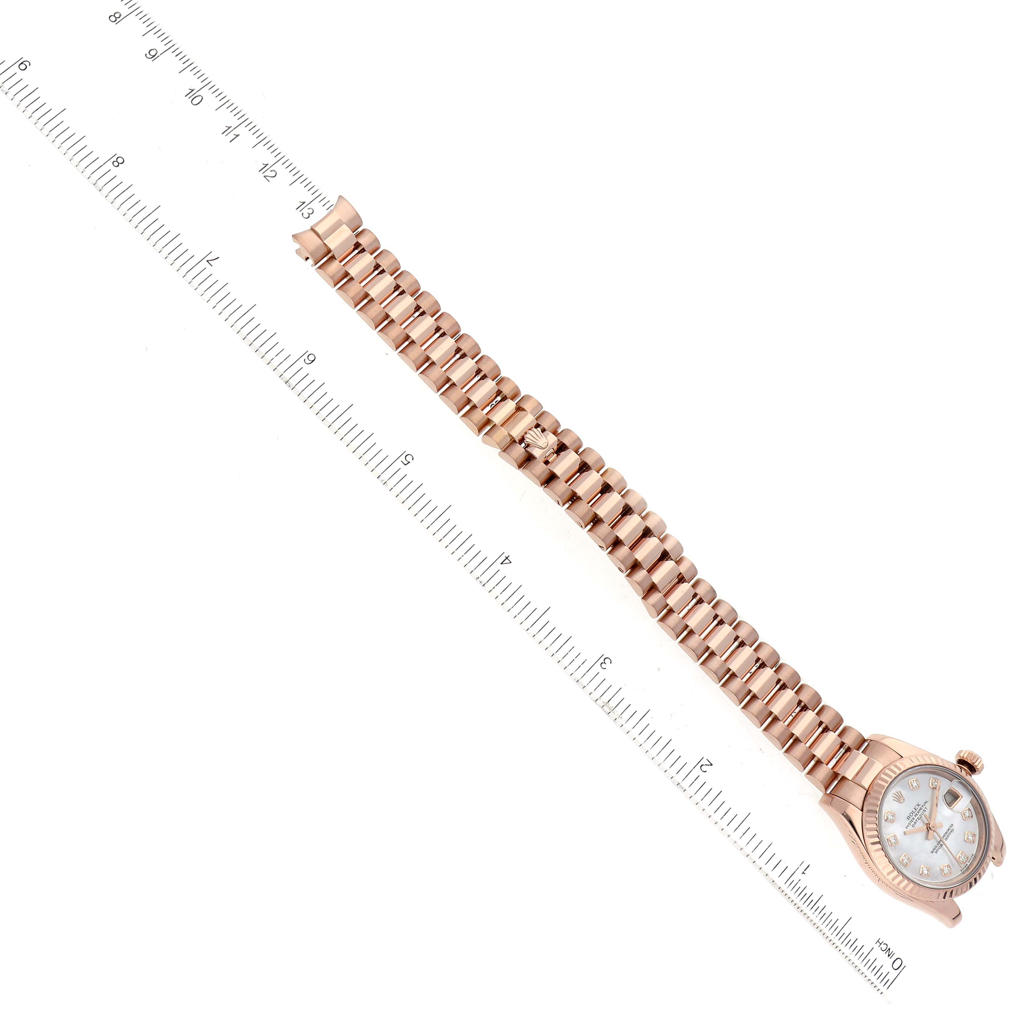 The Rolex President 179175F Women's Rose Gold Mother of Pearl Dial 179175F Women's Rose Gold Mother of Pearl Dial watch is shown from an overhead angle, displaying the full bracelet and face alongside a ruler for size reference.