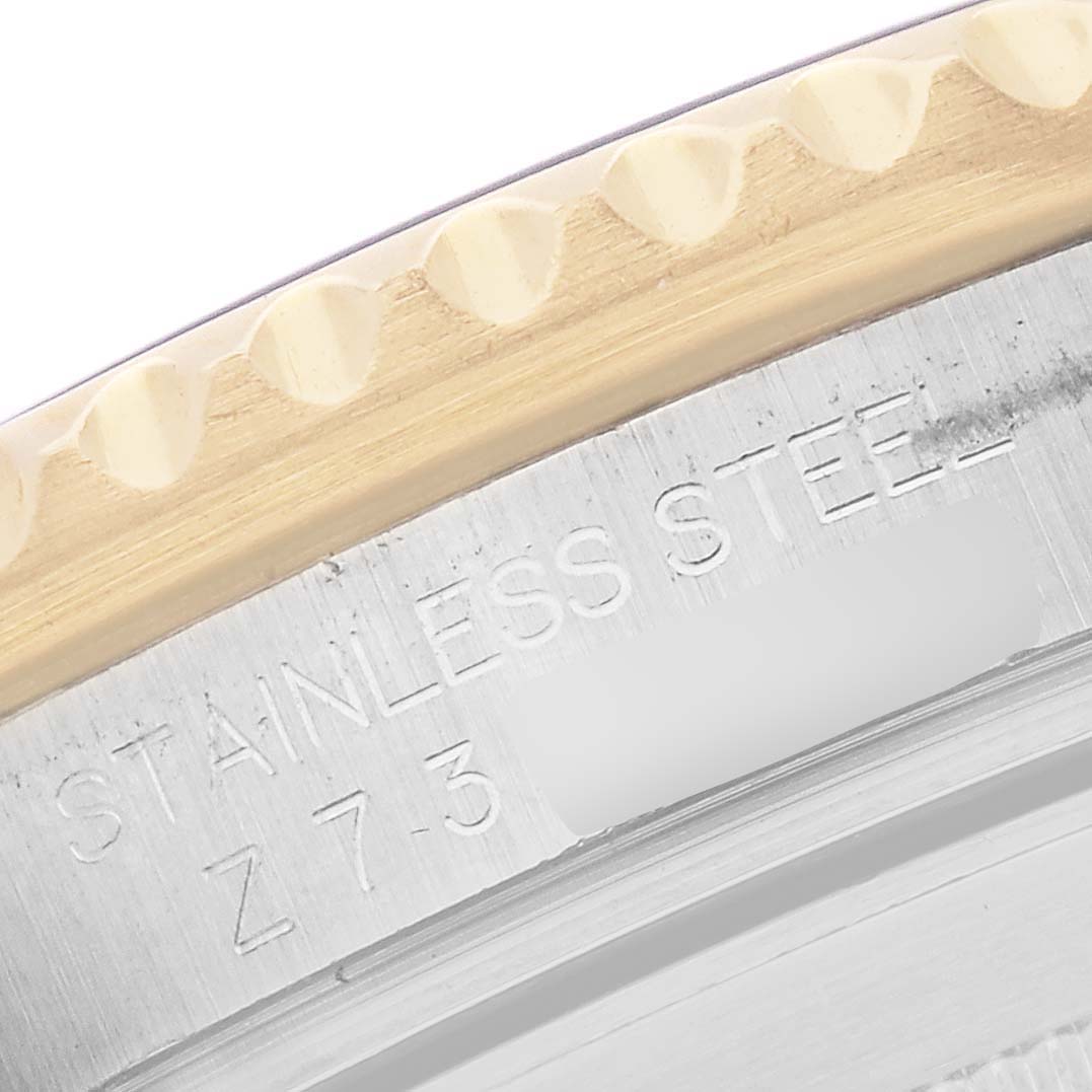 The image shows a close-up of the Rolex Submariner 16613 Men
s Steel and Gold (two tone) Blue Dial 16613 Men
s Steel and Gold (two tone) Blue Dial
s stainless steel case with engraved text and the edge of the bezel.