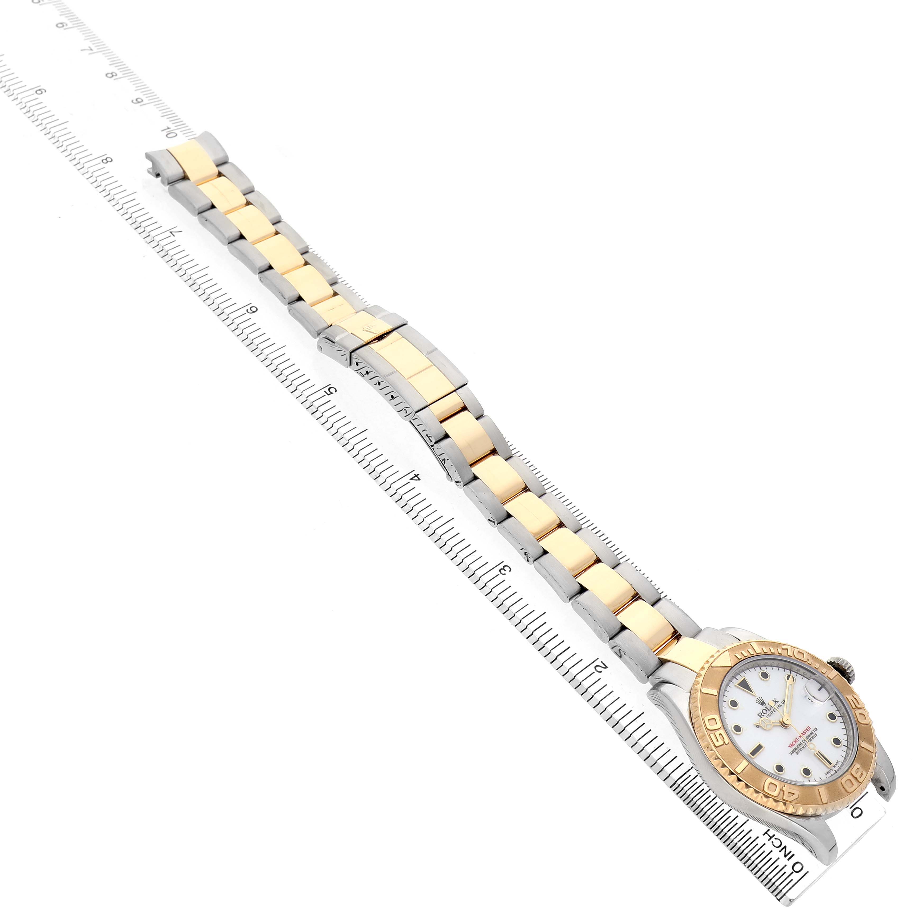 The Rolex Yacht-Master 168623 Men's Steel and Gold (two tone) White Dial is shown diagonally, displaying the watch face, bezel, and two-tone bracelet alongside a ruler for scale.