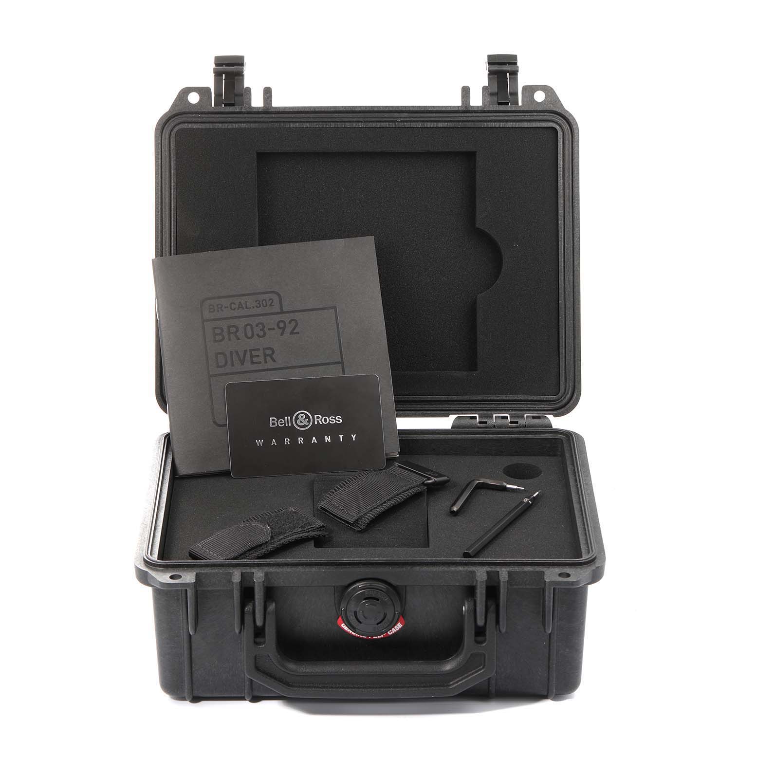 The image shows Bell & Ross Diver model accessories, including manuals, straps, and tools, in an open protective case, viewed frontally.