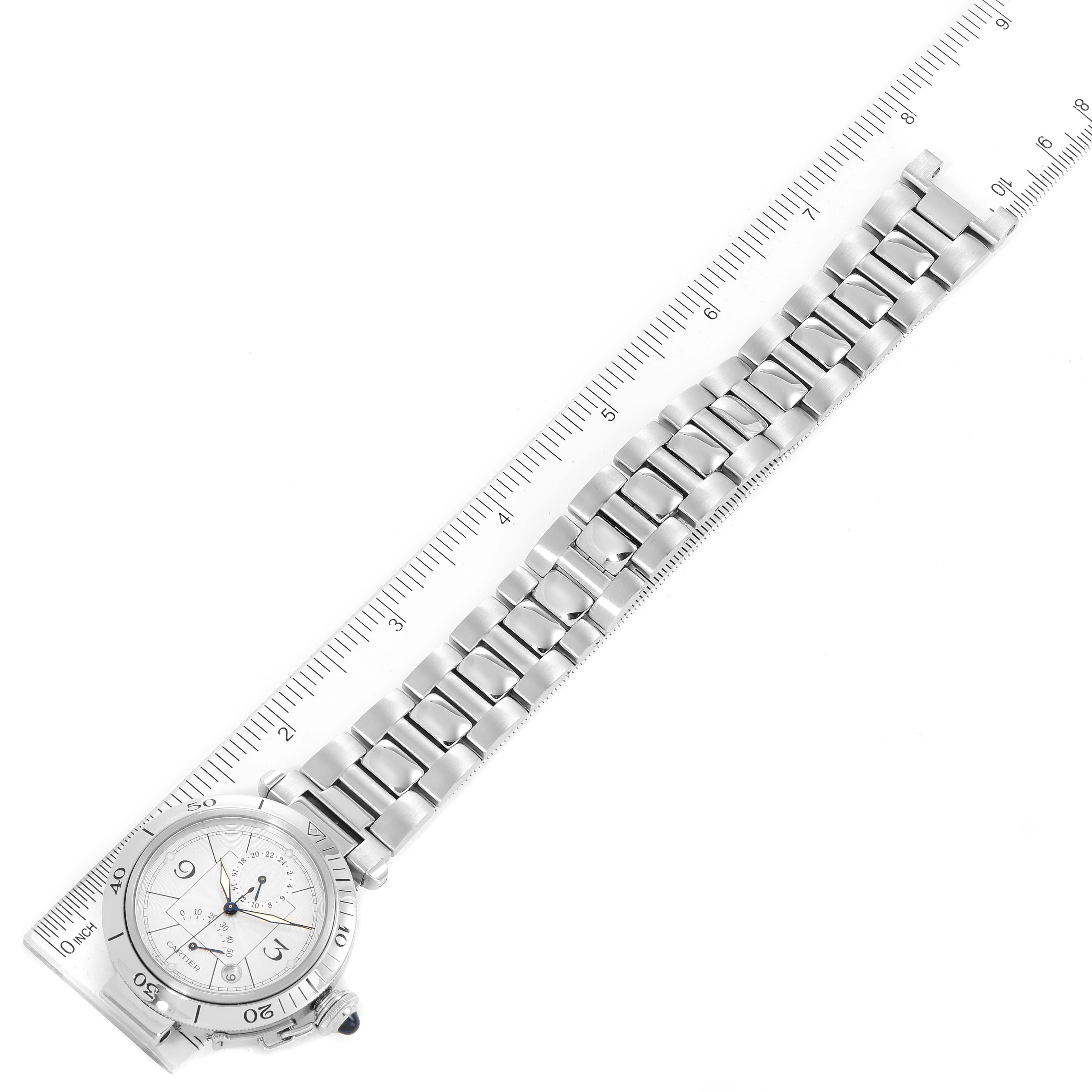 The image shows a Cartier Pasha W31037H3 Men
s Stainless Steel Silver Dial W31037H3 Men
s Stainless Steel Silver Dial watch laid flat with a full view of the face and bracelet alongside a ruler for scale.