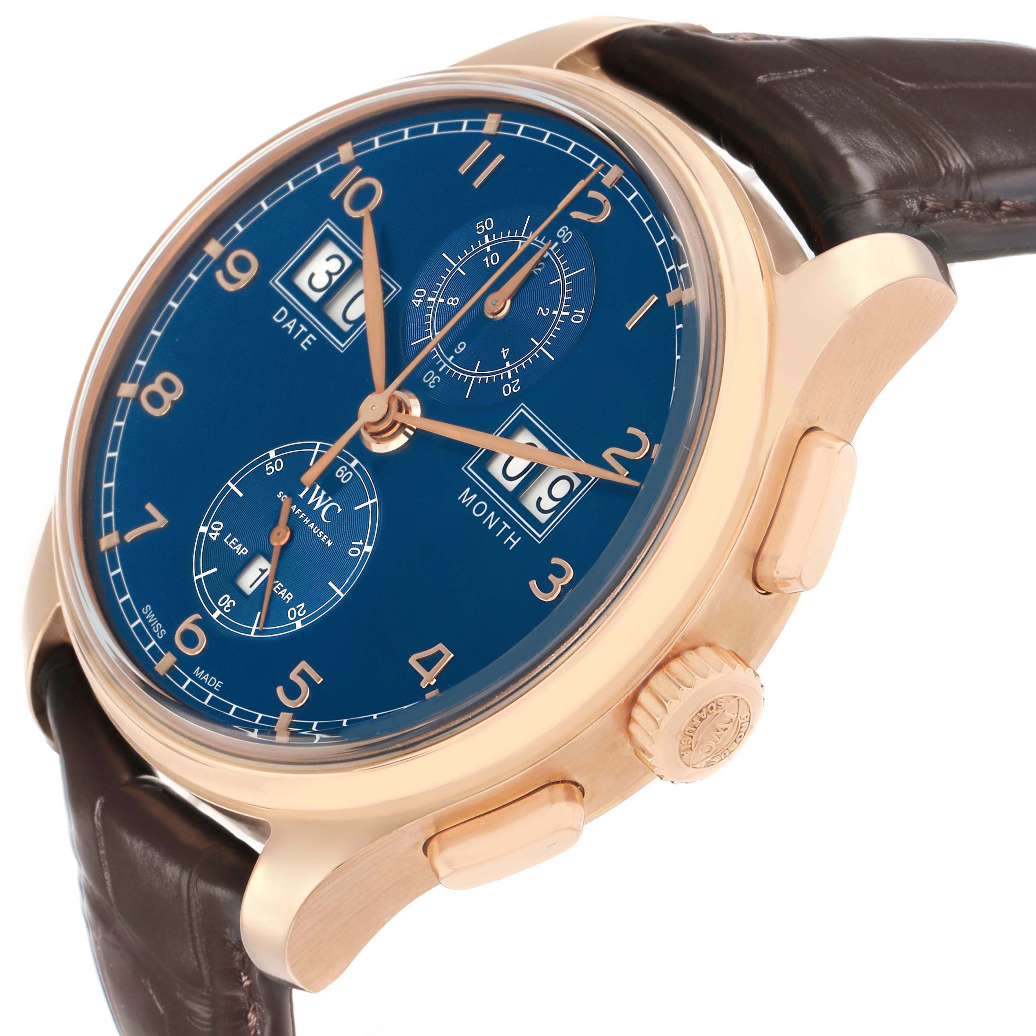 The IWC Portuguese IW397204 Men's Rose Gold Blue Dial watch is shown at an angled side view, highlighting the blue dial, gold case, and brown leather strap.