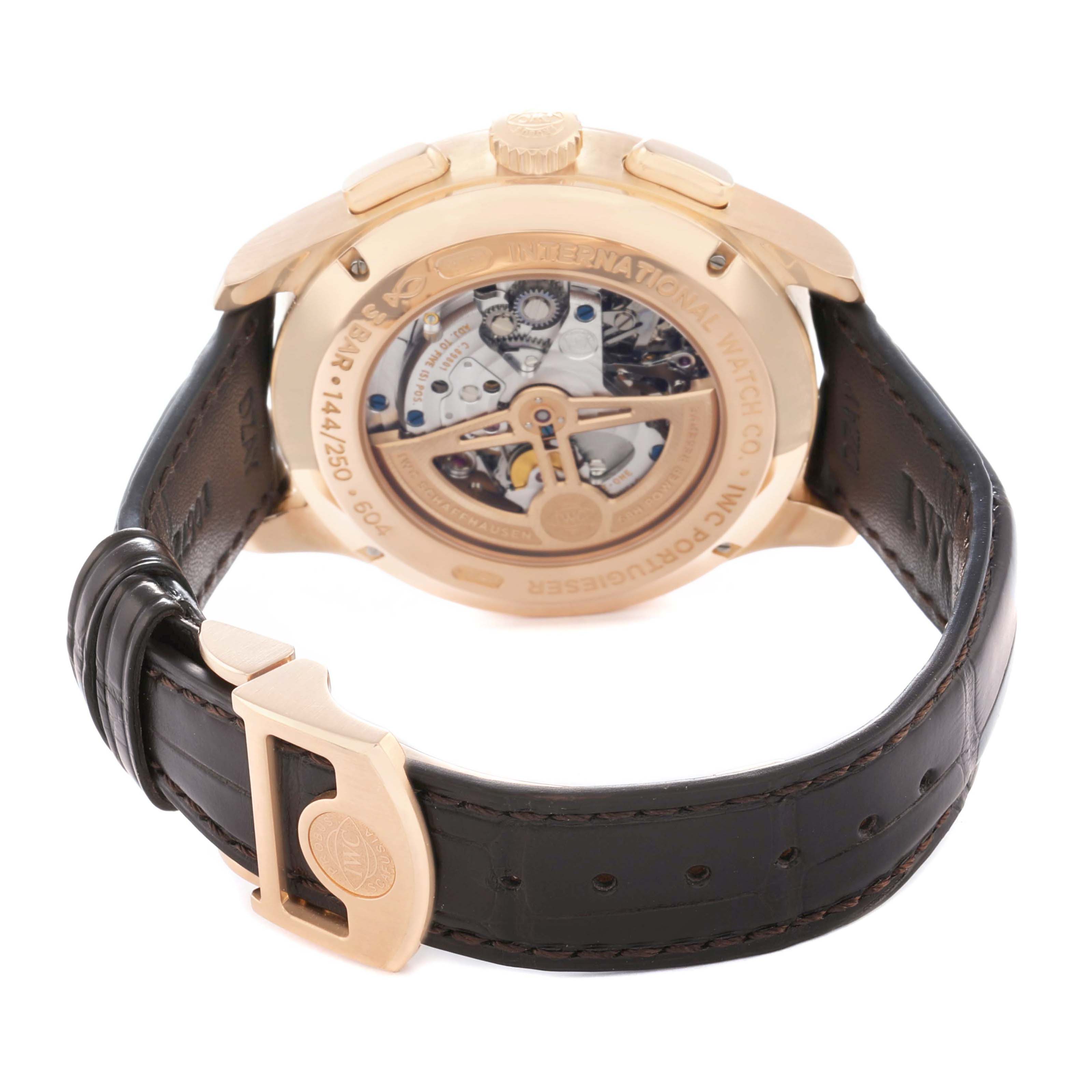 The IWC Portuguese IW397204 Men's Rose Gold Blue Dial watch is shown from the back, displaying the movement through a transparent case back and featuring a leather strap.