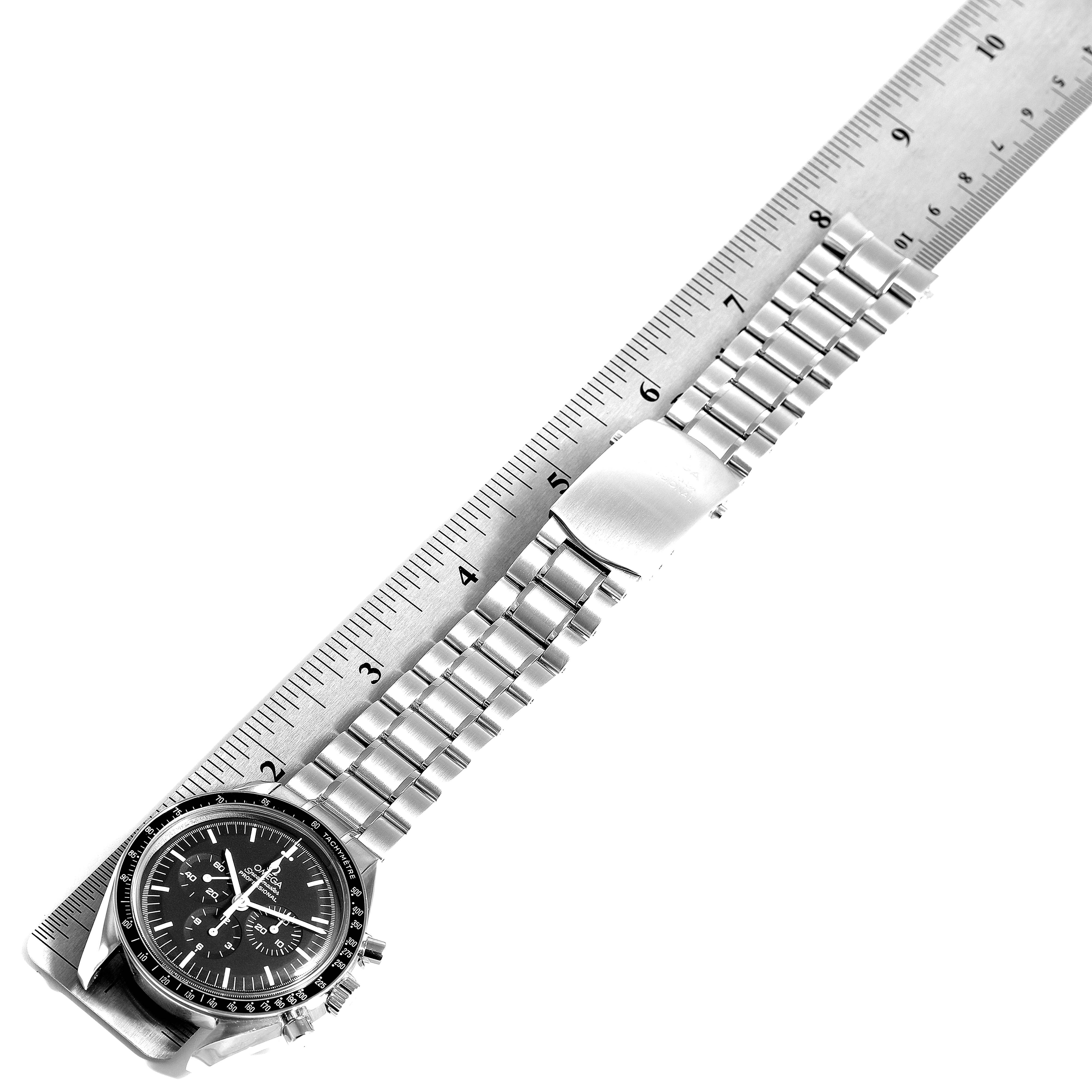 This image shows an Omega Speedmaster 3570.50.00 Men's Stainless Steel Black Dial 3570.50.00 Men's Stainless Steel Black Dial watch laid flat next to a ruler, highlighting its band and face.
