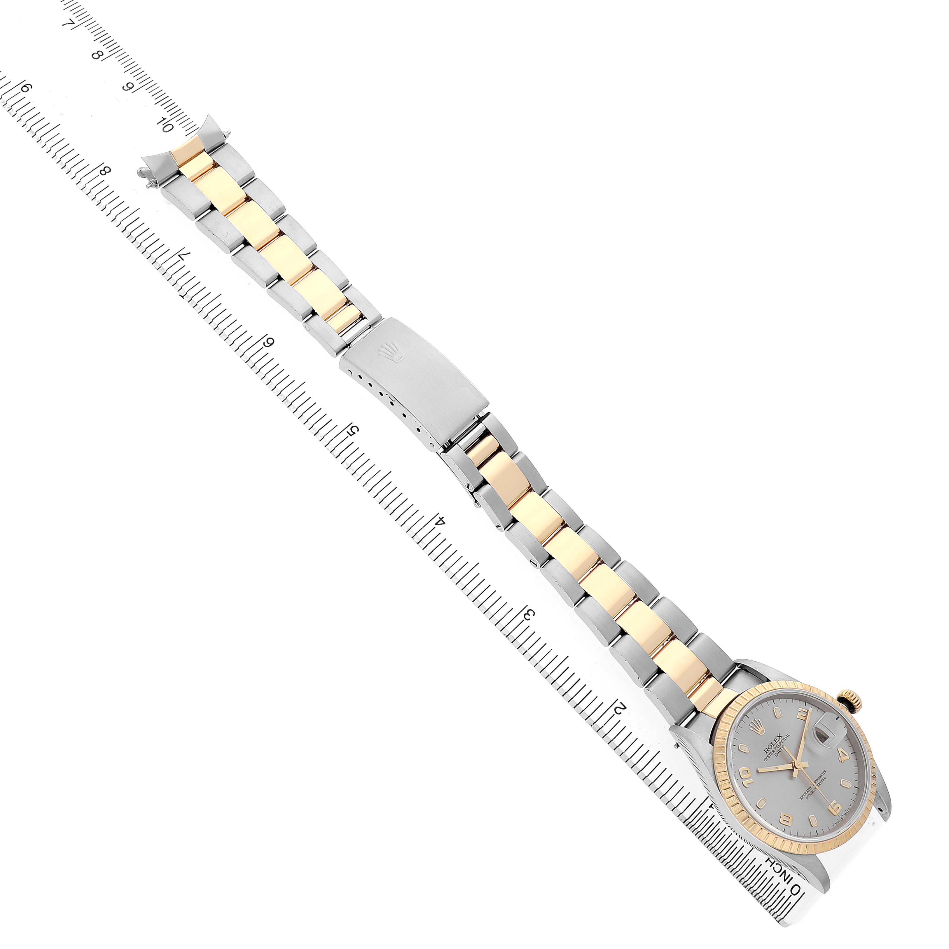 The image shows a Rolex Date 15223 Men's Steel and Gold (two tone) Silver Dial watch with a gold and silver bracelet, positioned diagonally alongside a ruler.