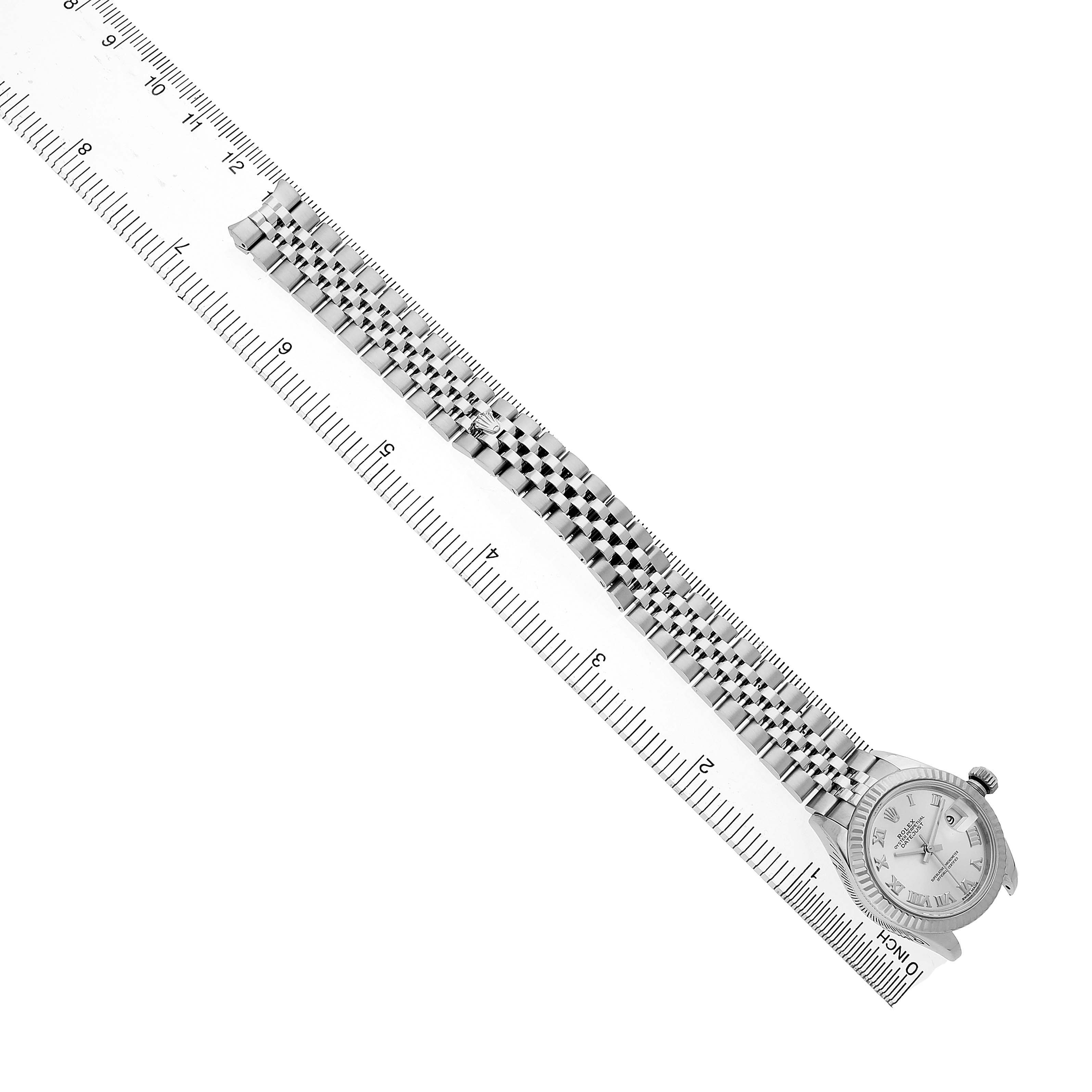 The Rolex Datejust 279174 Women's Stainless Steel Silver Dial watch is shown at an angle, displaying the full bracelet and watch face aligned with a ruler for scale.