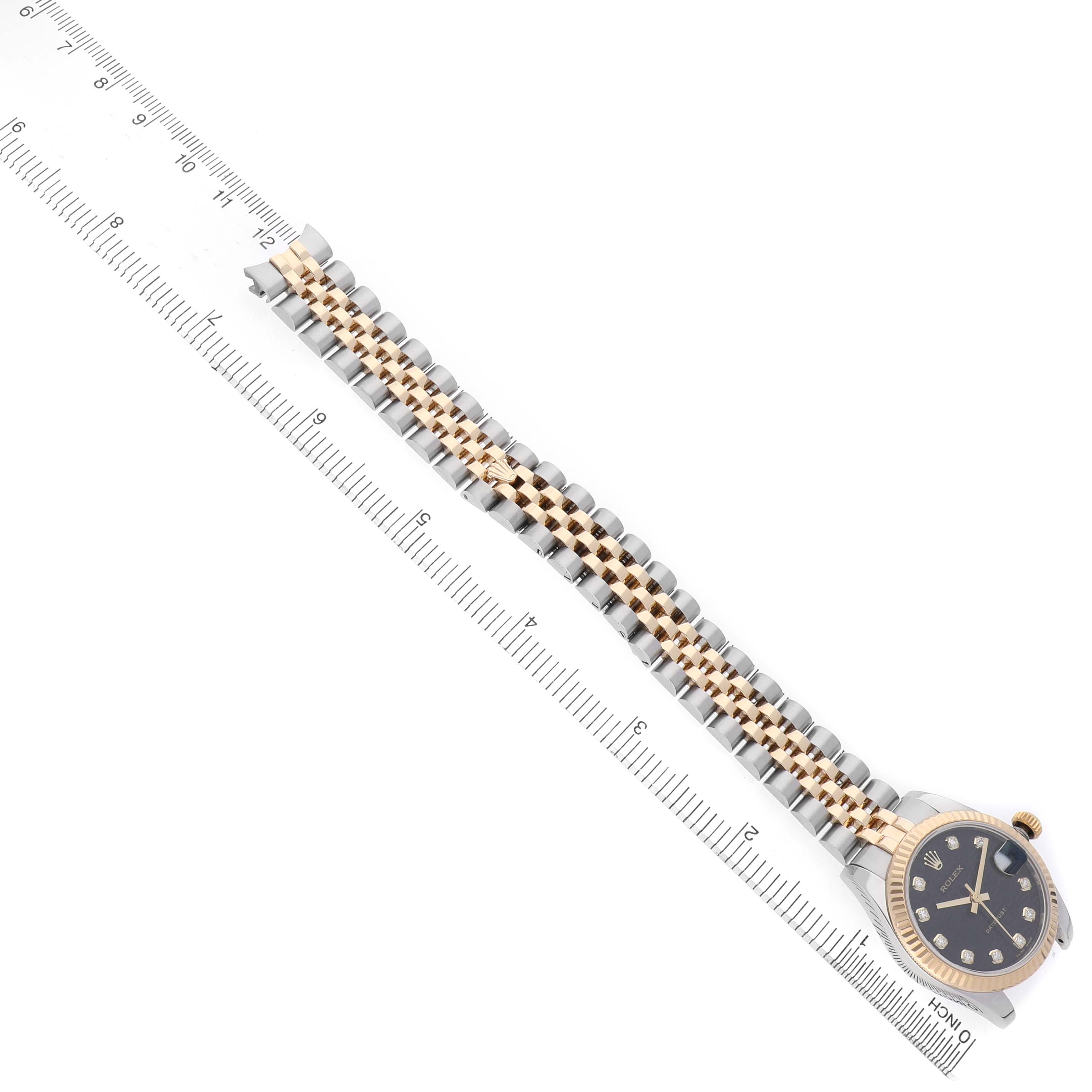 The image shows a Rolex Datejust 178273 Women's Stainless Steel Black Dial watch viewed from above, highlighting its two-tone bracelet and a portion of the dial alongside a ruler.