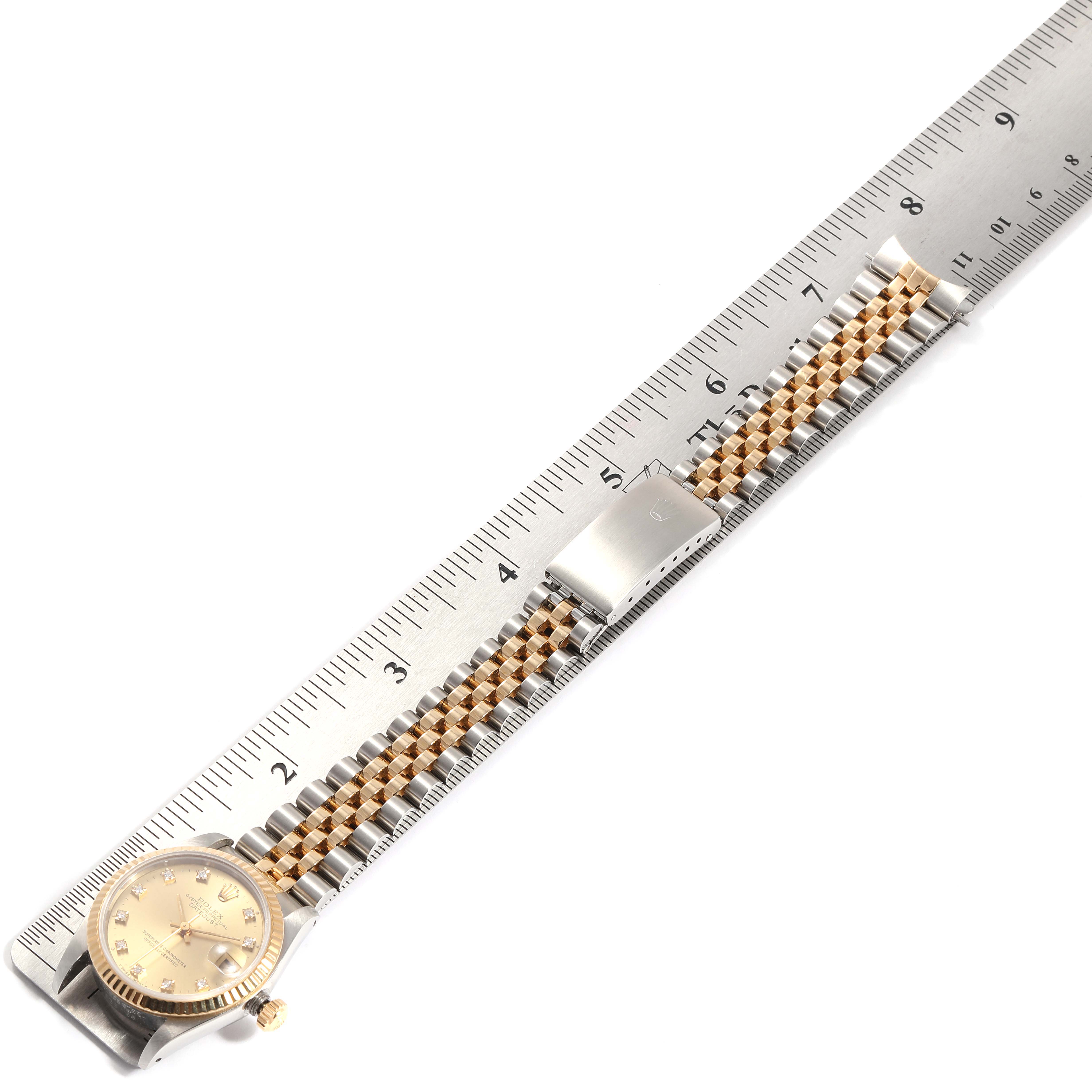 The Rolex Mid-Size 68273 Women's Steel and Gold (two tone) Champagne Dial 68273 Women's Steel and Gold (two tone) Champagne Dial model is shown from above with its face, crown, and bracelet laid flat alongside a ruler.