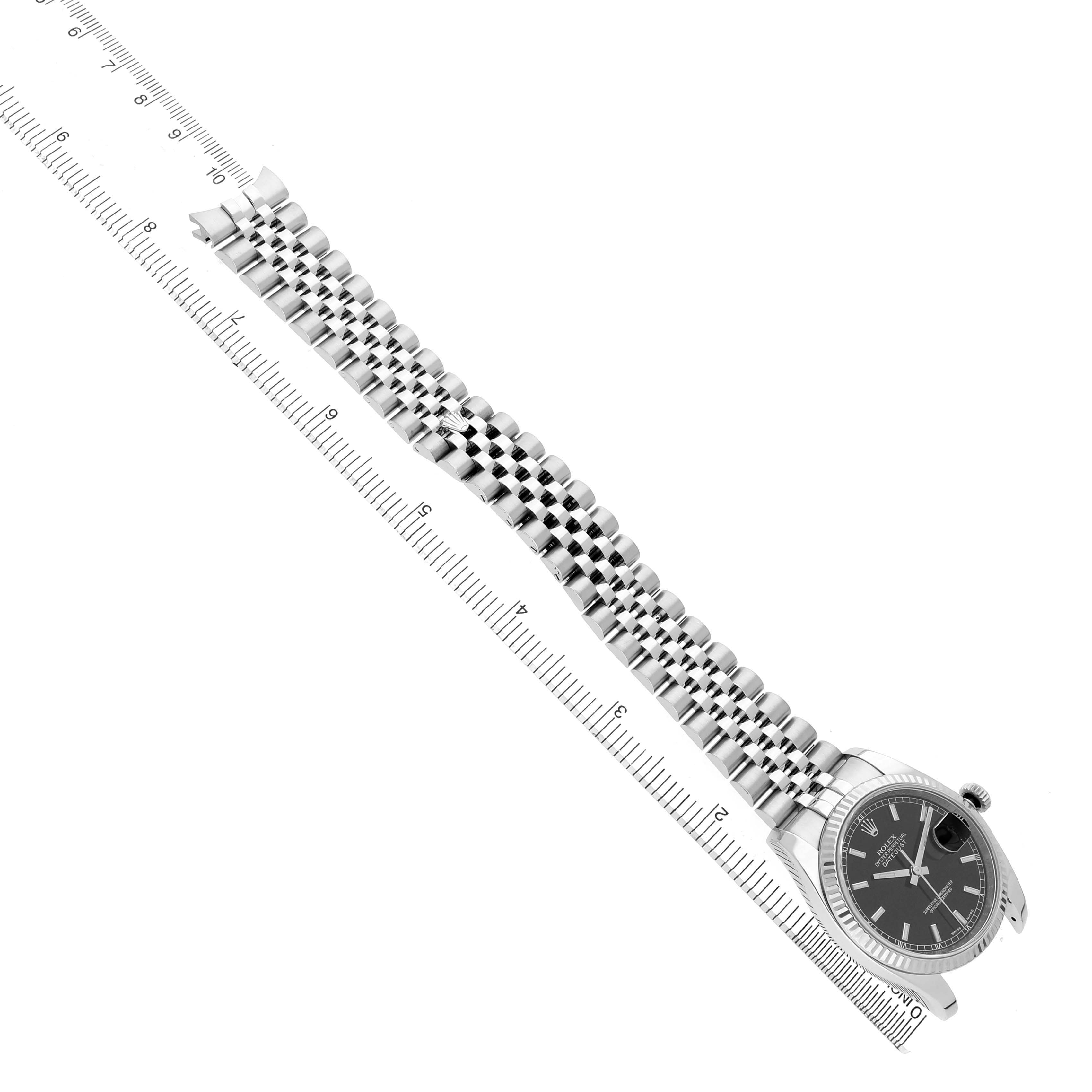 The Rolex Datejust 116234 Men's Stainless Steel Black Dial watch is shown at an angle showcasing the face, dial, and a metal bracelet alongside a ruler.