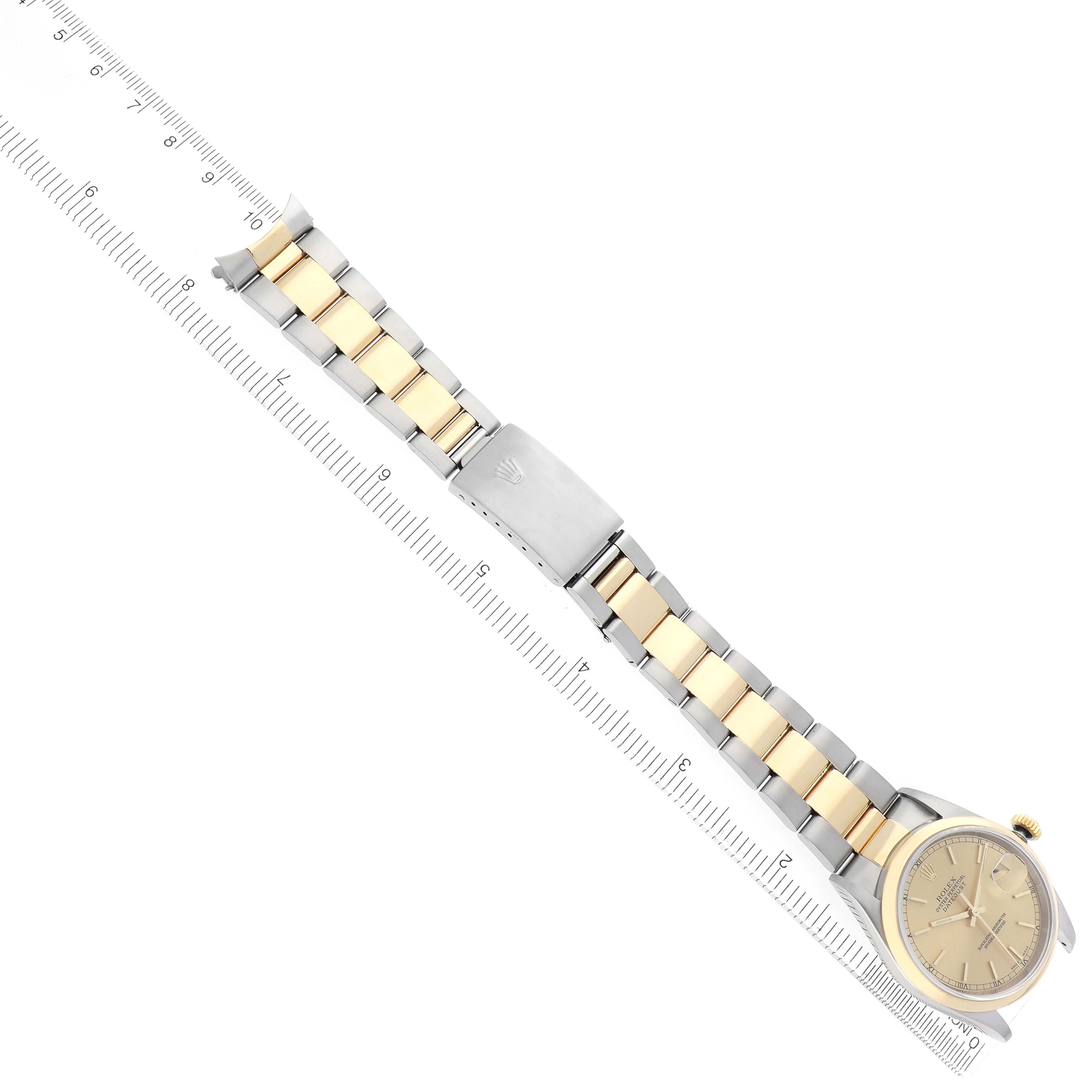 The Rolex Datejust 16203 Men
s Steel and Gold (two tone) Champagne Dial 16203 Men
s Steel and Gold (two tone) Champagne Dial watch is shown from an overhead angle, displaying the full bracelet and dial beside a ruler for scale.