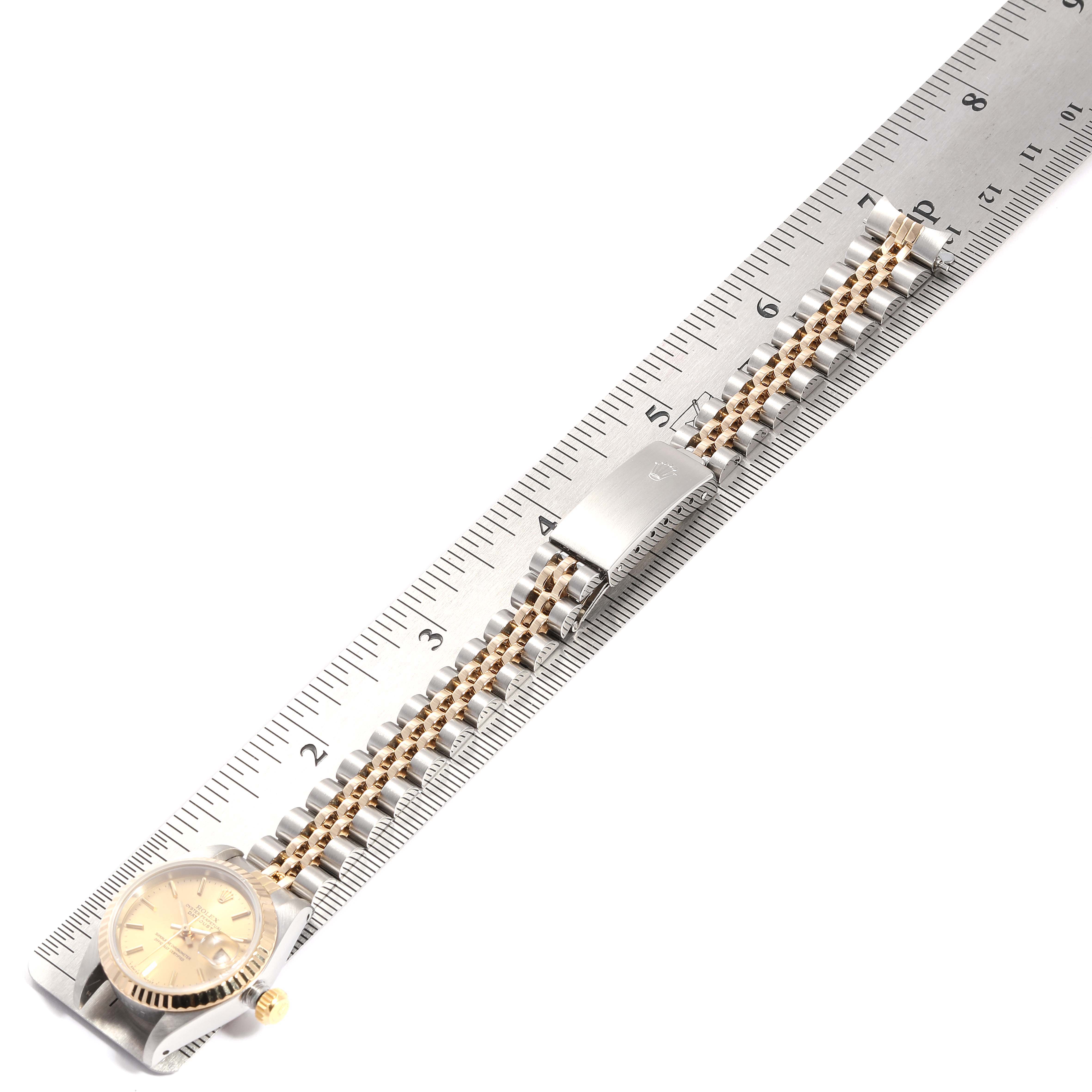 The image shows a top-down view of a Rolex Datejust 69173 Women
s Steel and Gold (two tone) Champagne Dial 69173 Women
s Steel and Gold (two tone) Champagne Dial watch lying flat on a ruler, displaying its bracelet and clasp.