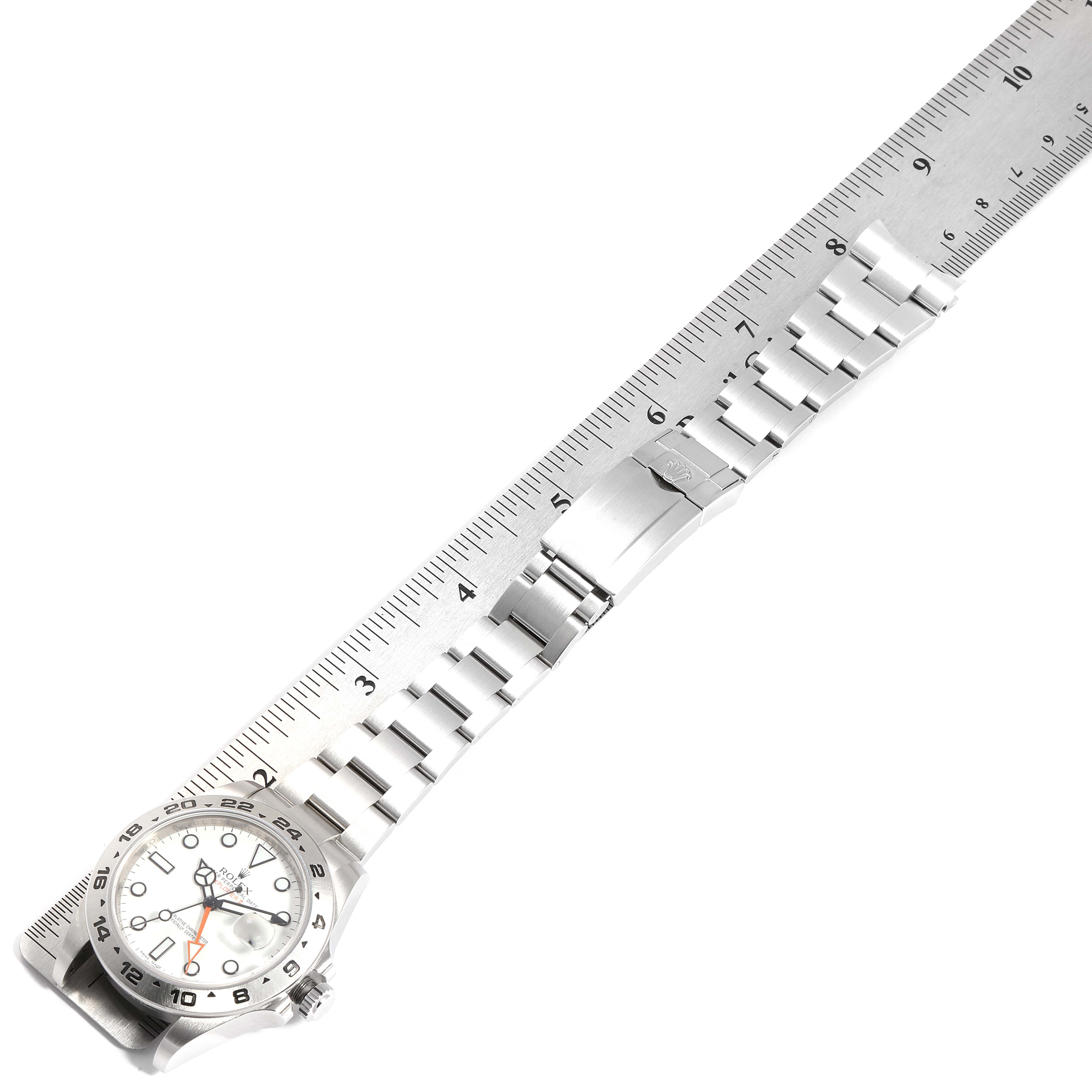 The Rolex Explorer 216570 Men's Stainless Steel White Dial 216570 Men's Stainless Steel White Dial watch is shown at an angle with the entire watch band and clasp visible alongside a measuring ruler.