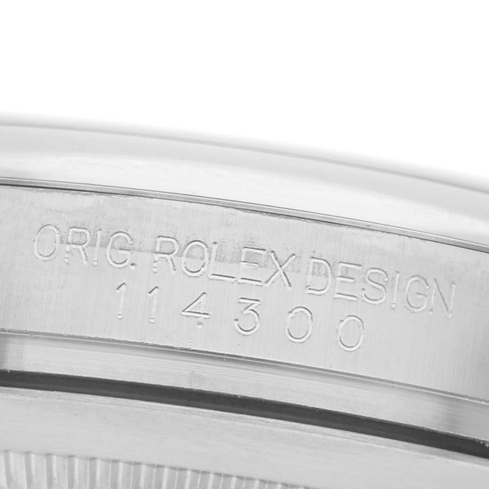 The image shows an angled close-up of the side of a Rolex Oyster Perpetual 114300 Men
s Stainless Steel Black Dial 114300 Men
s Stainless Steel Black Dial watch, focusing on the engraved design number.
