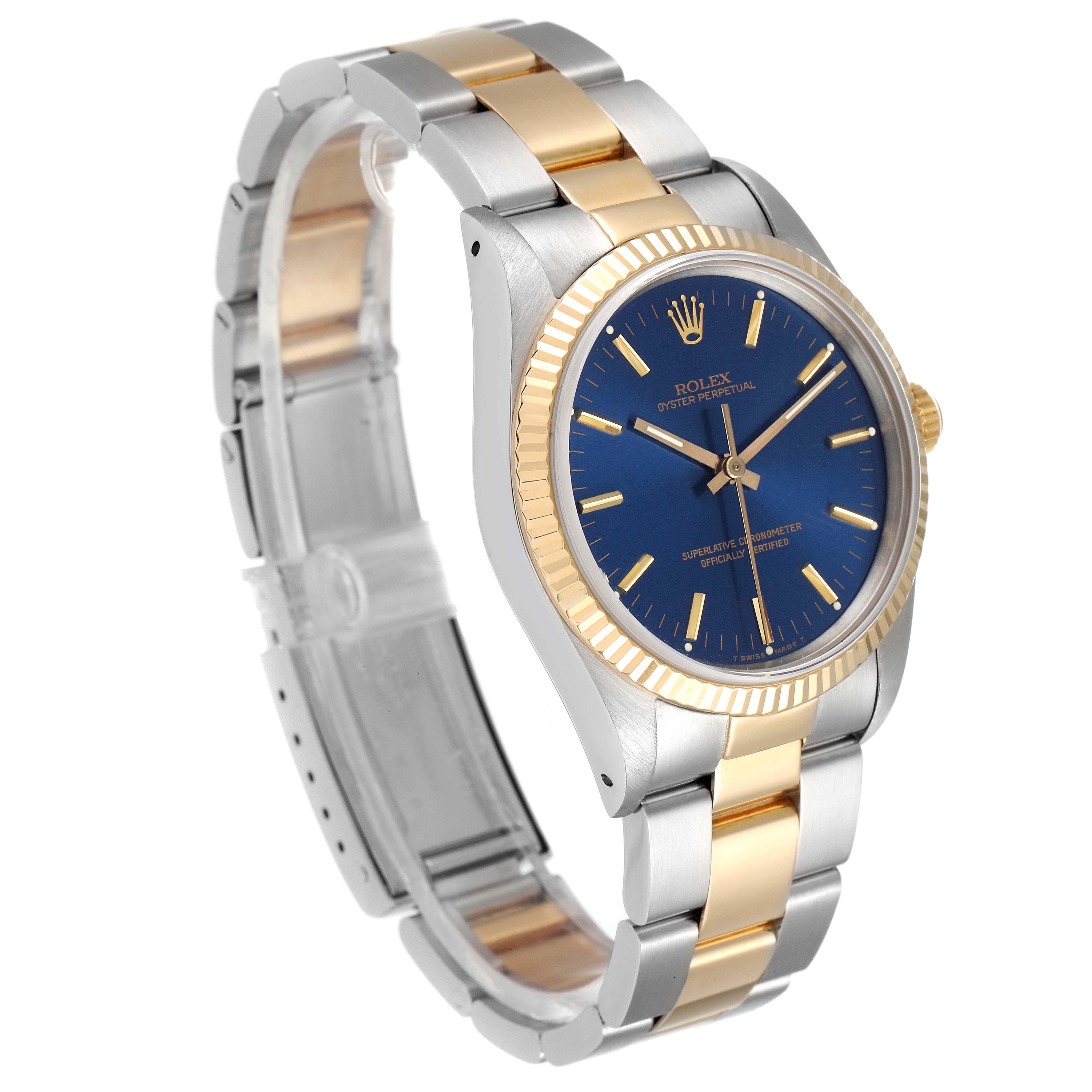 The Rolex Oyster Perpetual 14233 Men's Steel and Gold (two tone) Blue Dial 14233 Men's Steel and Gold (two tone) Blue Dial watch is shown at an angled side view, highlighting its blue dial, two-tone bracelet, and fluted bezel.