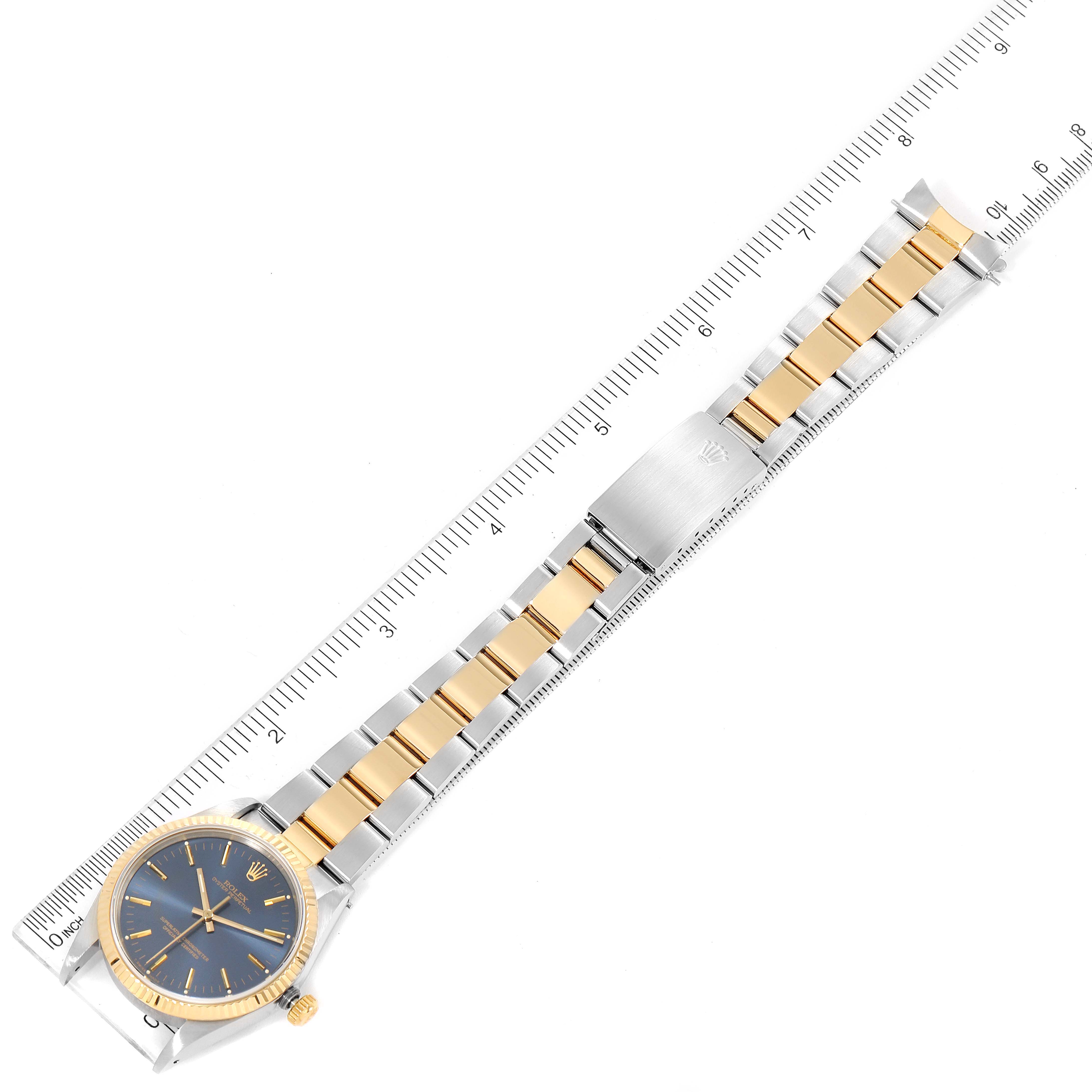 The image shows a full view of the Rolex Oyster Perpetual 14233 Men's Steel and Gold (two tone) Blue Dial 14233 Men's Steel and Gold (two tone) Blue Dial watch, including the dial, bracelet, and clasp, with a ruler for scale.