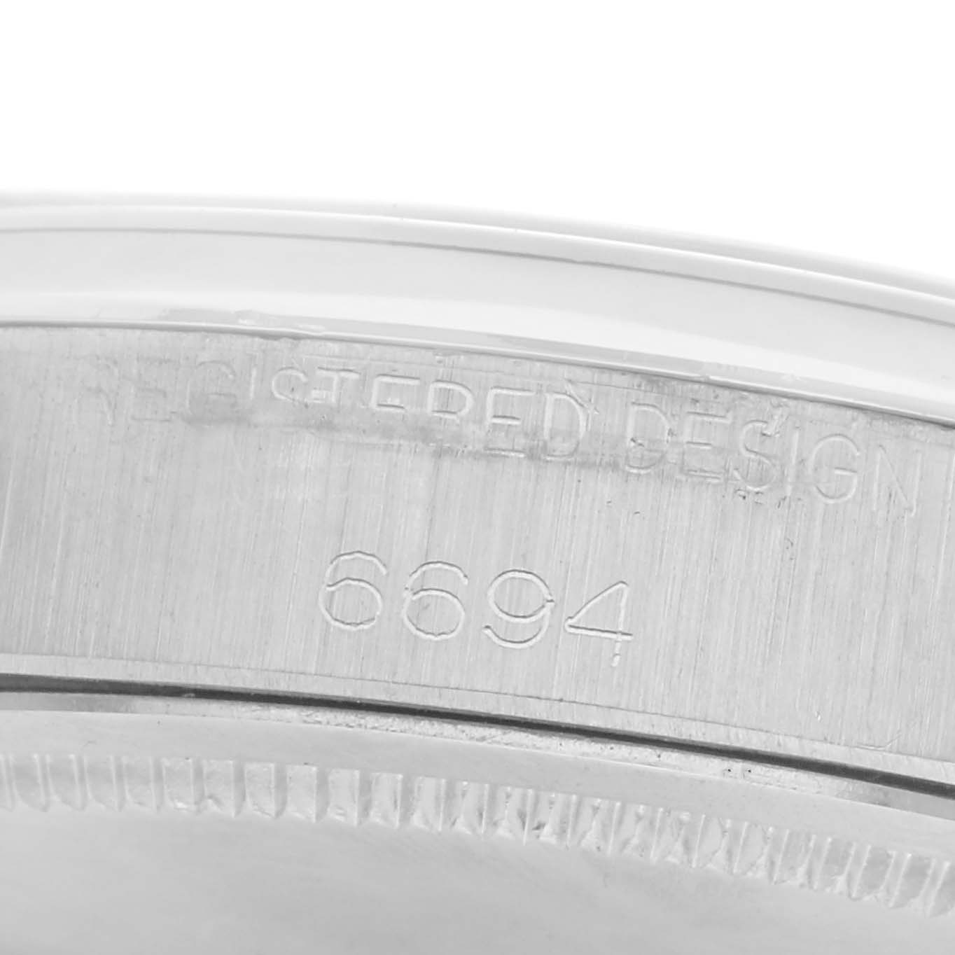 The image shows a close-up of the case back edge of a Rolex Date 6694 Men
s Stainless Steel Silver Dial 6694 Men
s Stainless Steel Silver Dial model, highlighting the model number "6694" and "REGISTERED DESIGN" engraving.
