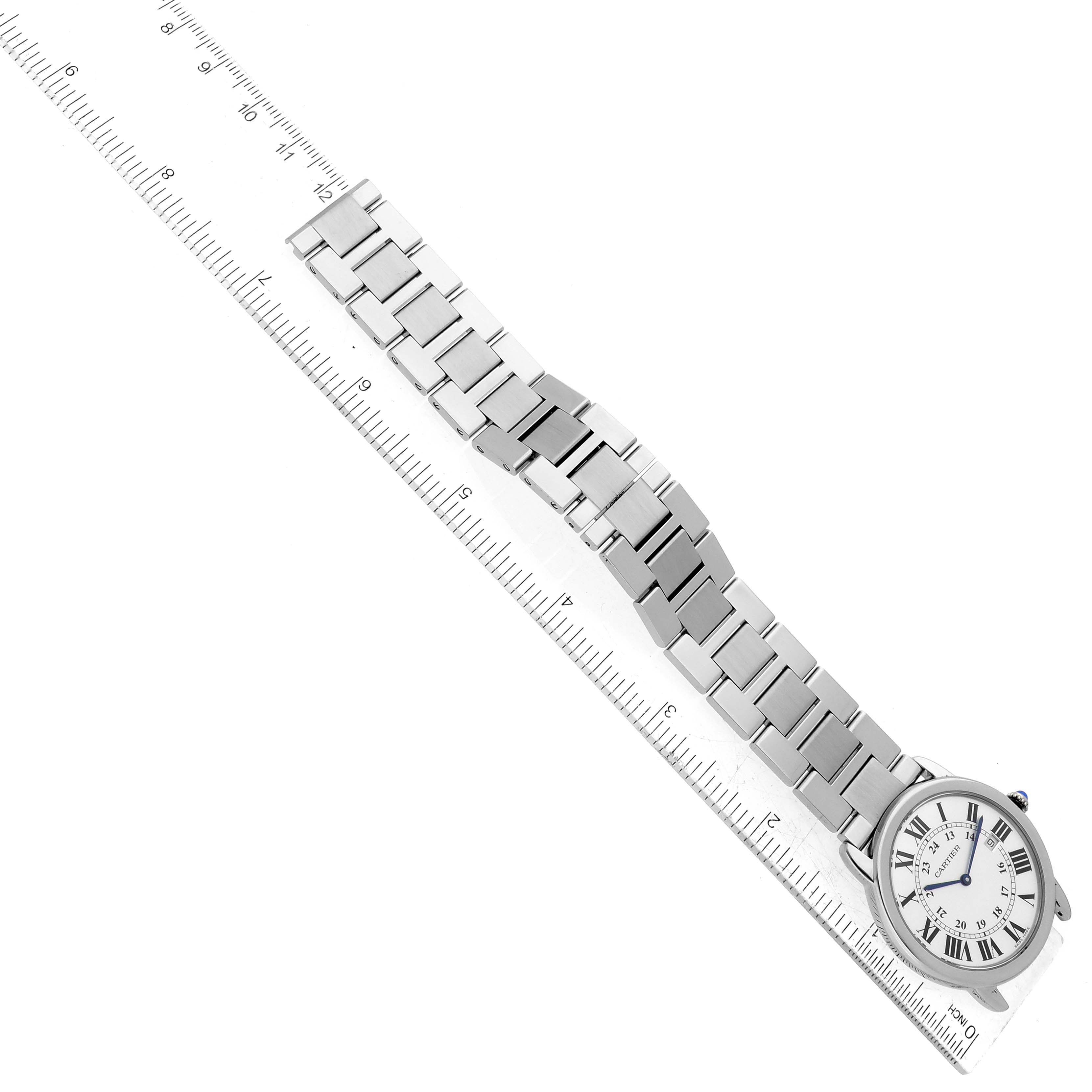The image shows a top-down view of a Cartier Ronde W6701005 Men
s Stainless Steel Silver Dial W6701005 Men
s Stainless Steel Silver Dial watch, including its face and metal bracelet, placed alongside a ruler.