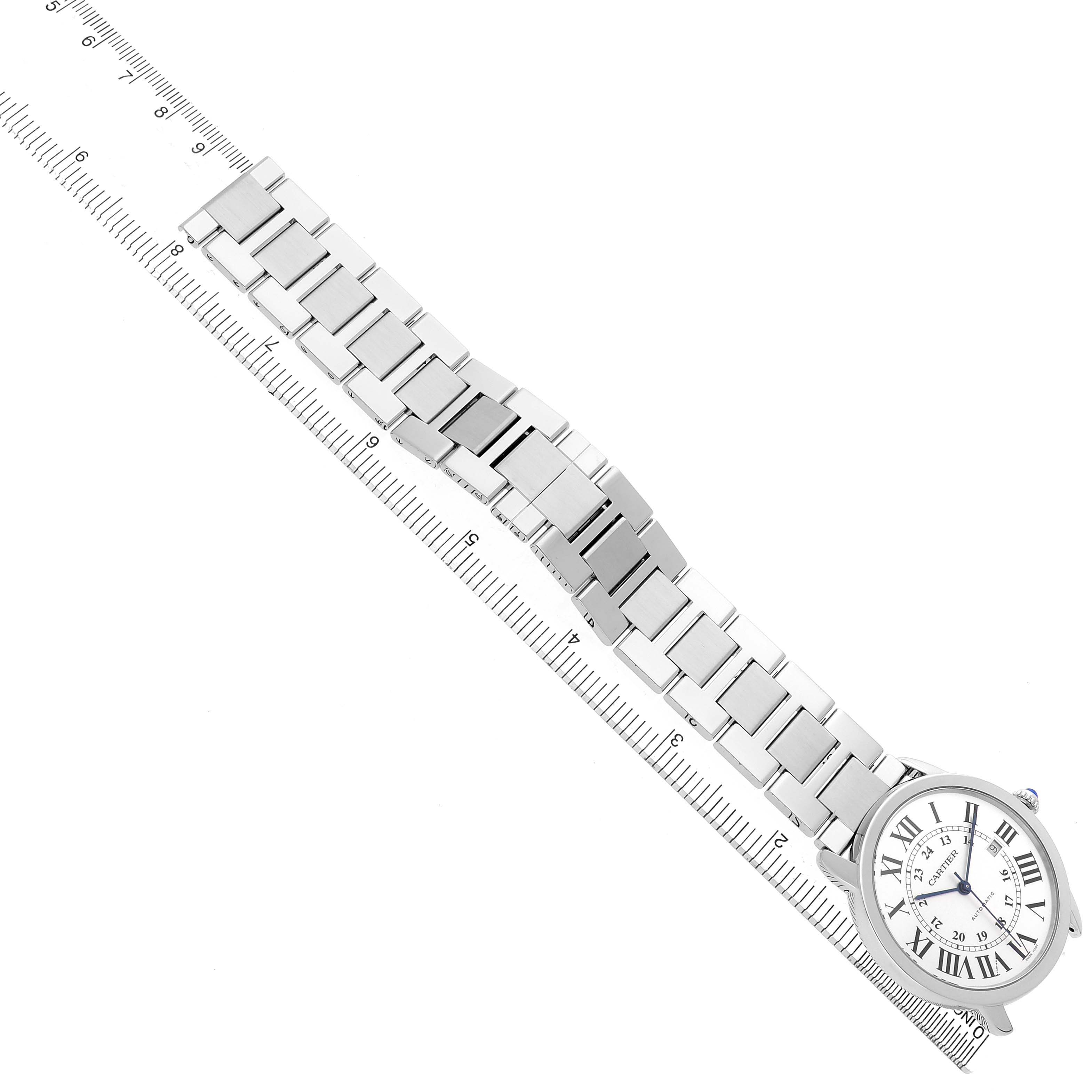 The Cartier Ronde W6701011 Men's Stainless Steel Silver Dial watch is shown from a top view, displaying its round face and metal bracelet, alongside a ruler for scale.