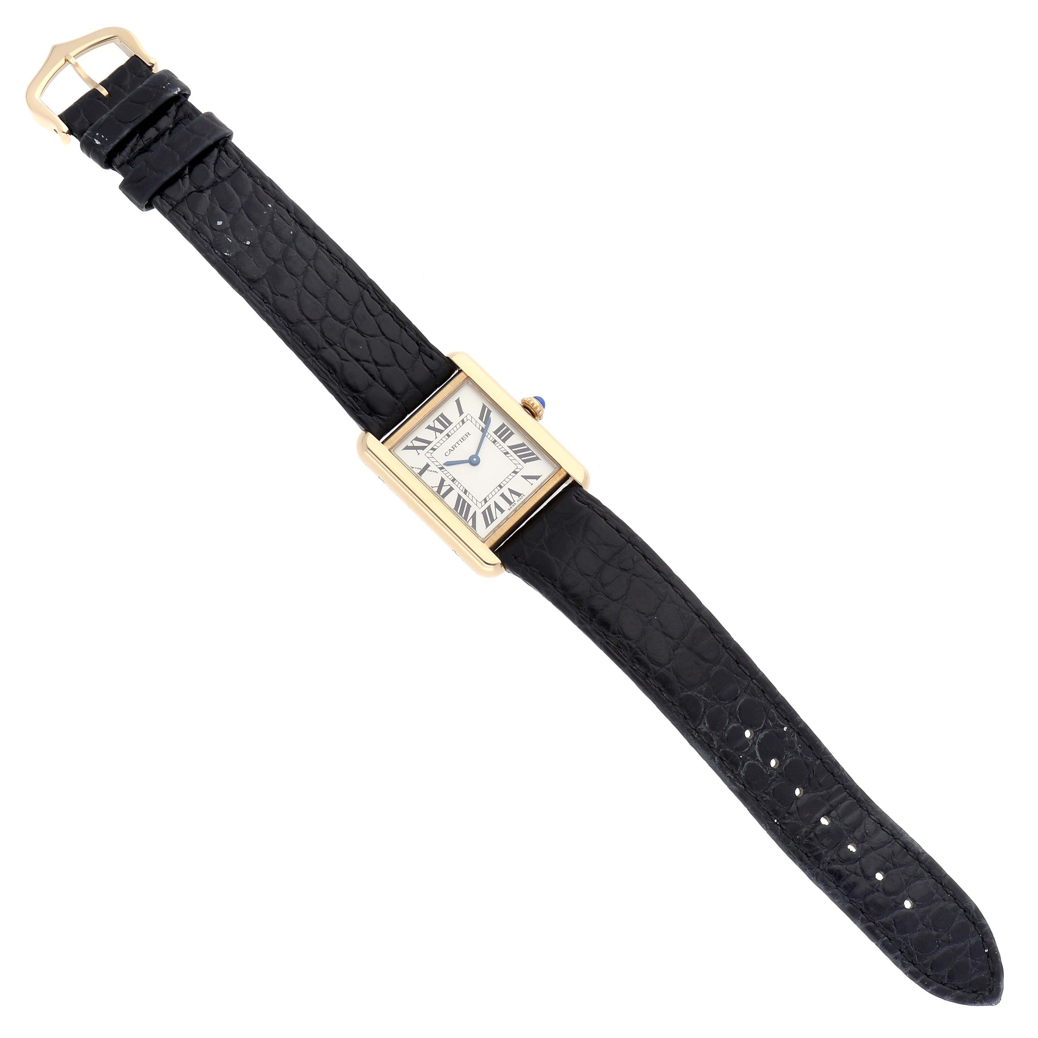 The Cartier Tank Solo W1018755 Women
s Yellow Gold Silver Dial W1018755 Women
s Yellow Gold Silver Dial watch is shown top-down, featuring its rectangular dial, black strap, and gold case.