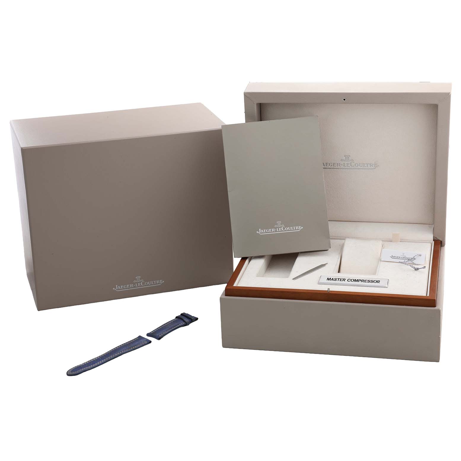 The image shows the packaging and accessories of a Jaeger-LeCoultre Master Compressor, including a box and extra strap.