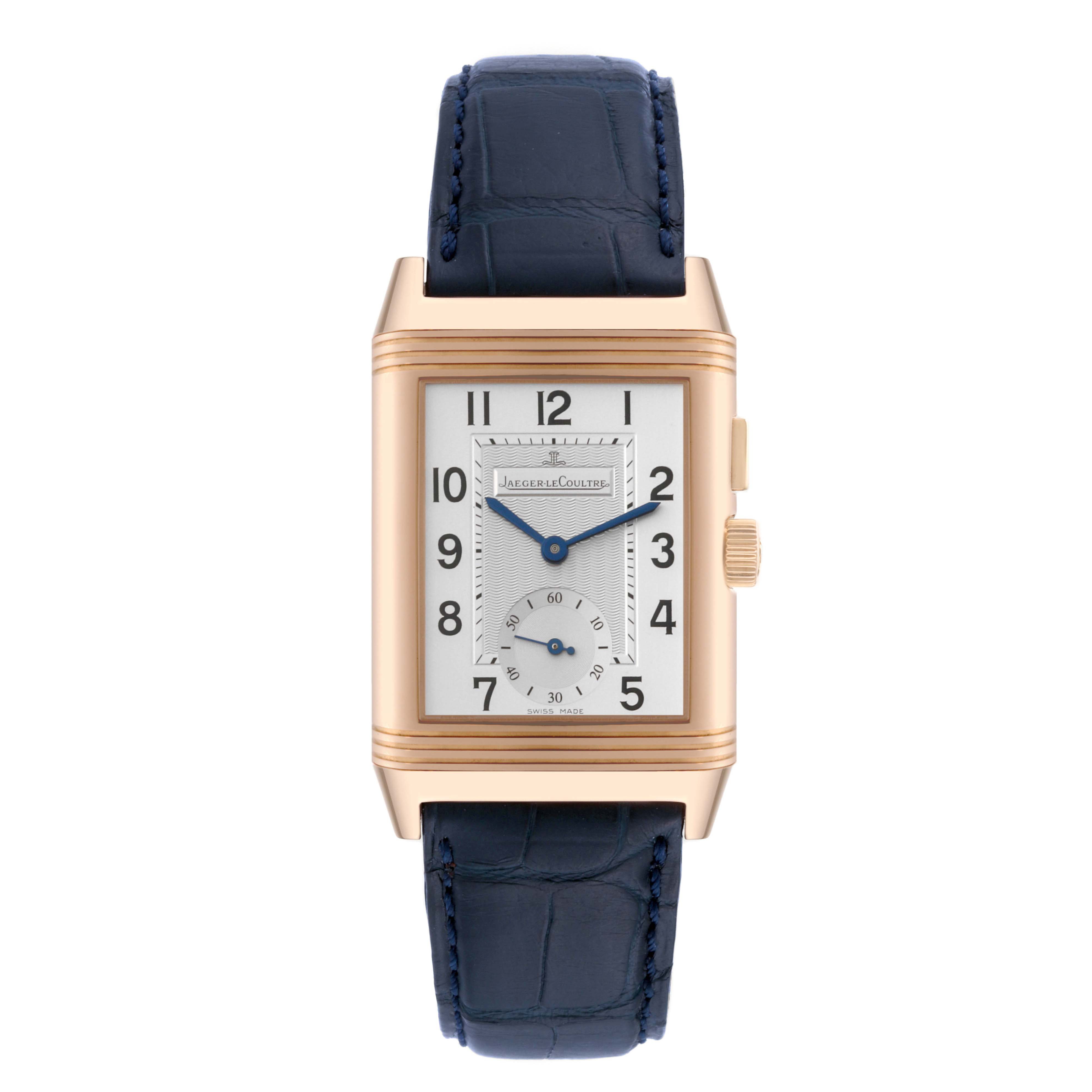 The image shows a Jaeger LeCoultre Reverso Q2712411 Men's Rose Gold Silver Dial Q2712411 Men's Rose Gold Silver Dial watch from a front angle, highlighting its rectangular dial, gold case, and blue leather strap.