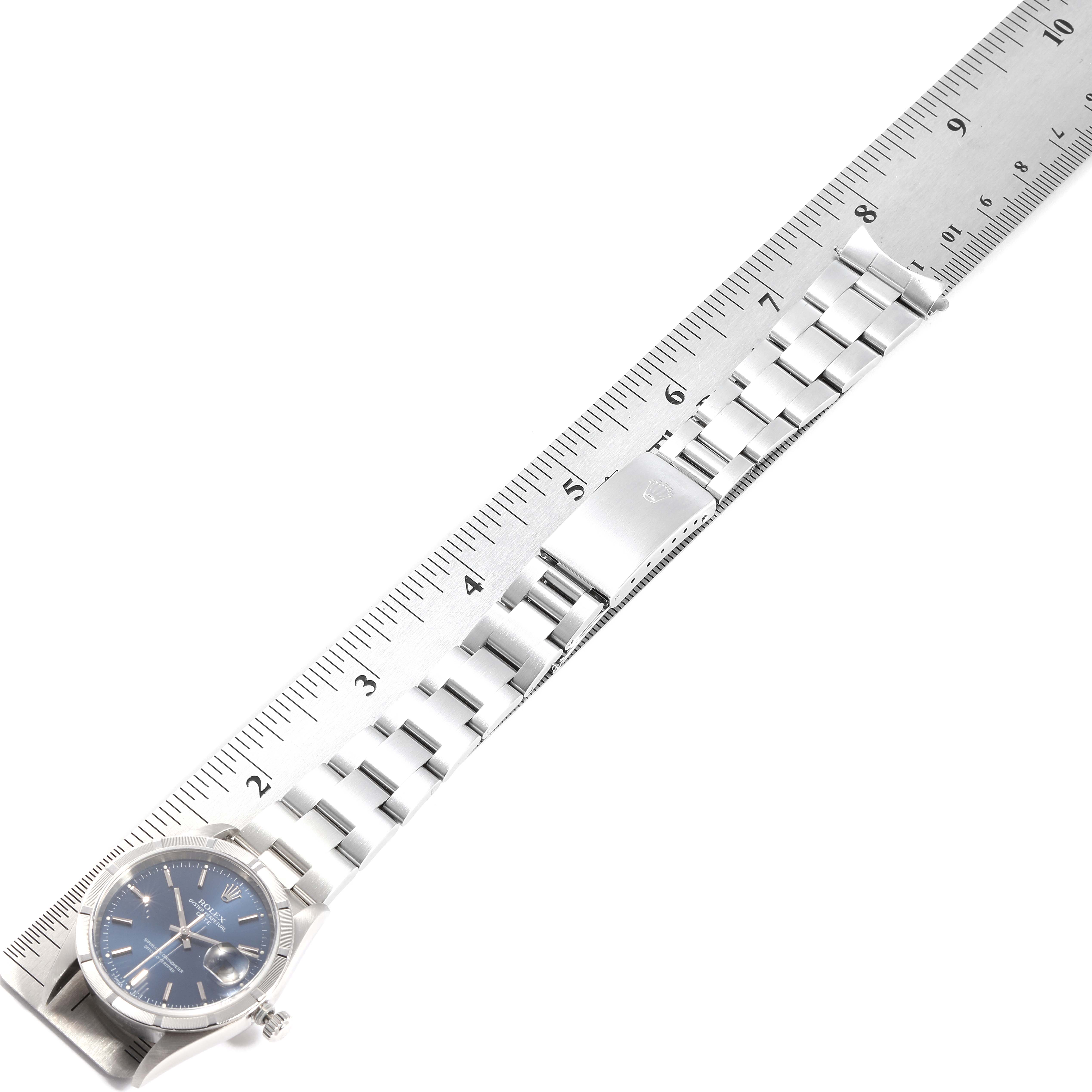 A Rolex Date 15210 Men's Stainless Steel Blue Dial 15210 Men's Stainless Steel Blue Dial model watch is displayed fully extended, showing the face, bracelet, clasp, and a ruler for scale.
