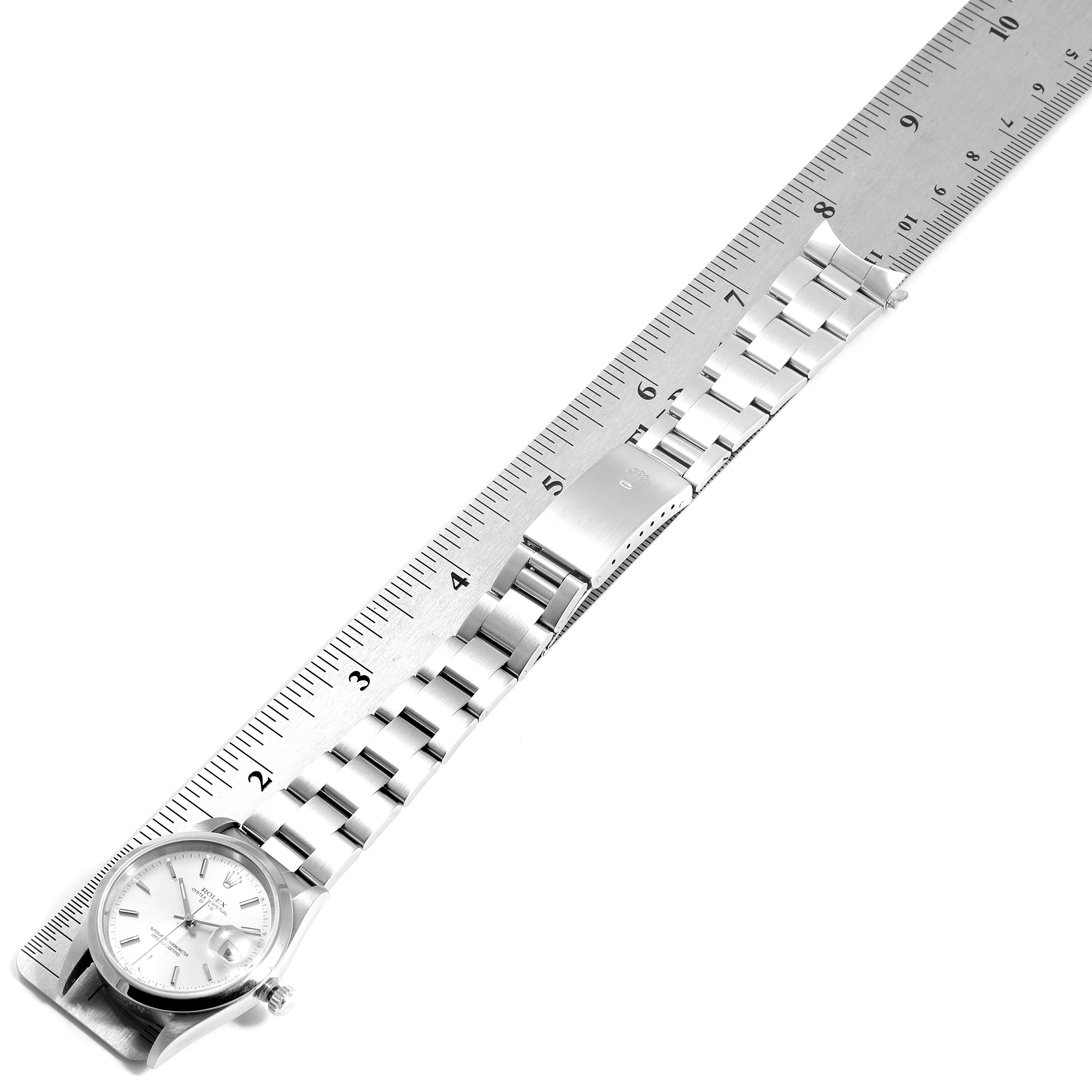 The Rolex Date 15200 Men's Stainless Steel Silver Dial 15200 Men's Stainless Steel Silver Dial model watch is shown from above, displaying the face, bracelet, and clasp next to a ruler.