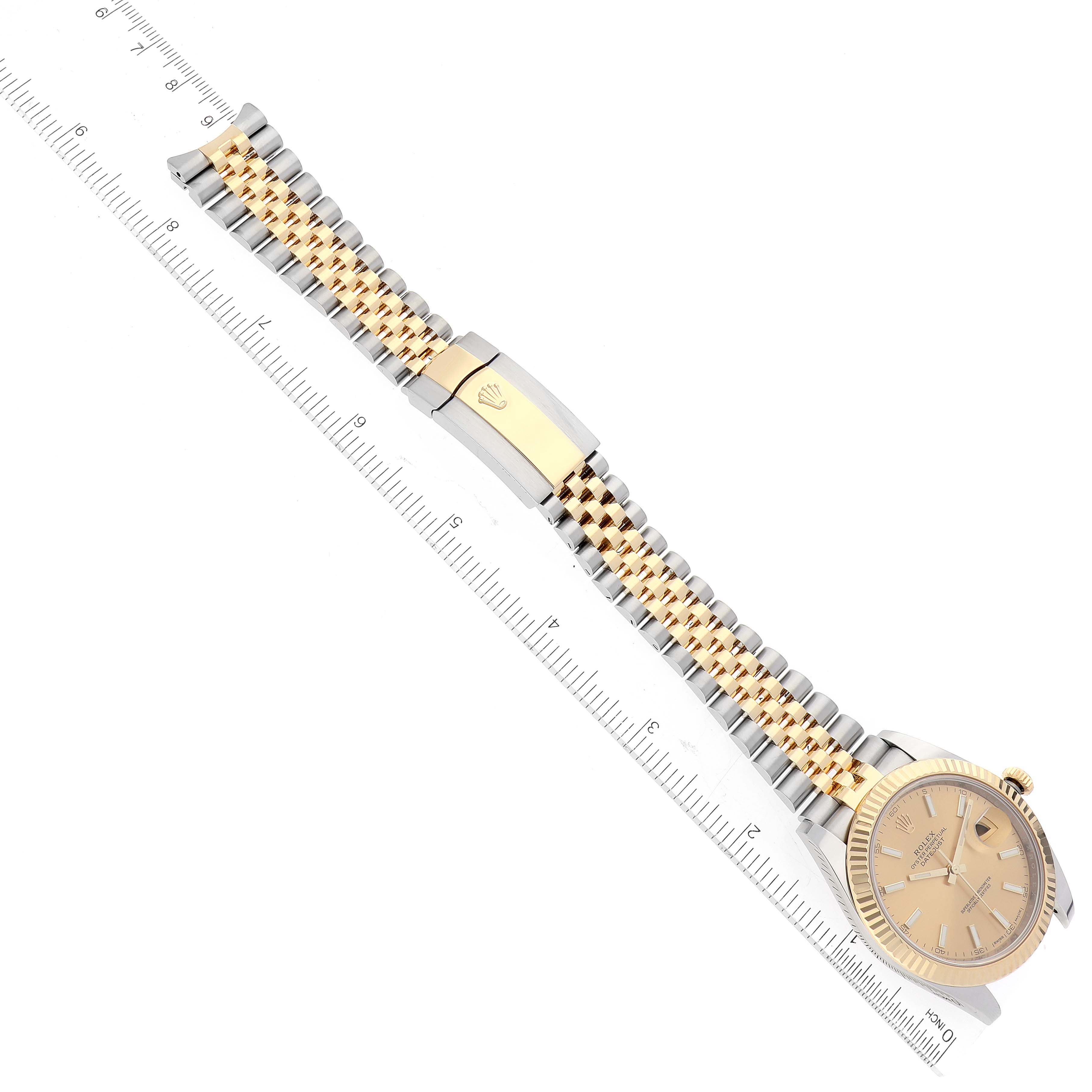 The Rolex Datejust 41 126333 Men's Steel and Gold (two tone) Champagne Dial 126333 Men's Steel and Gold (two tone) Champagne Dial watch is shown from a top-down angle with a focus on its face and metal bracelet next to a ruler.