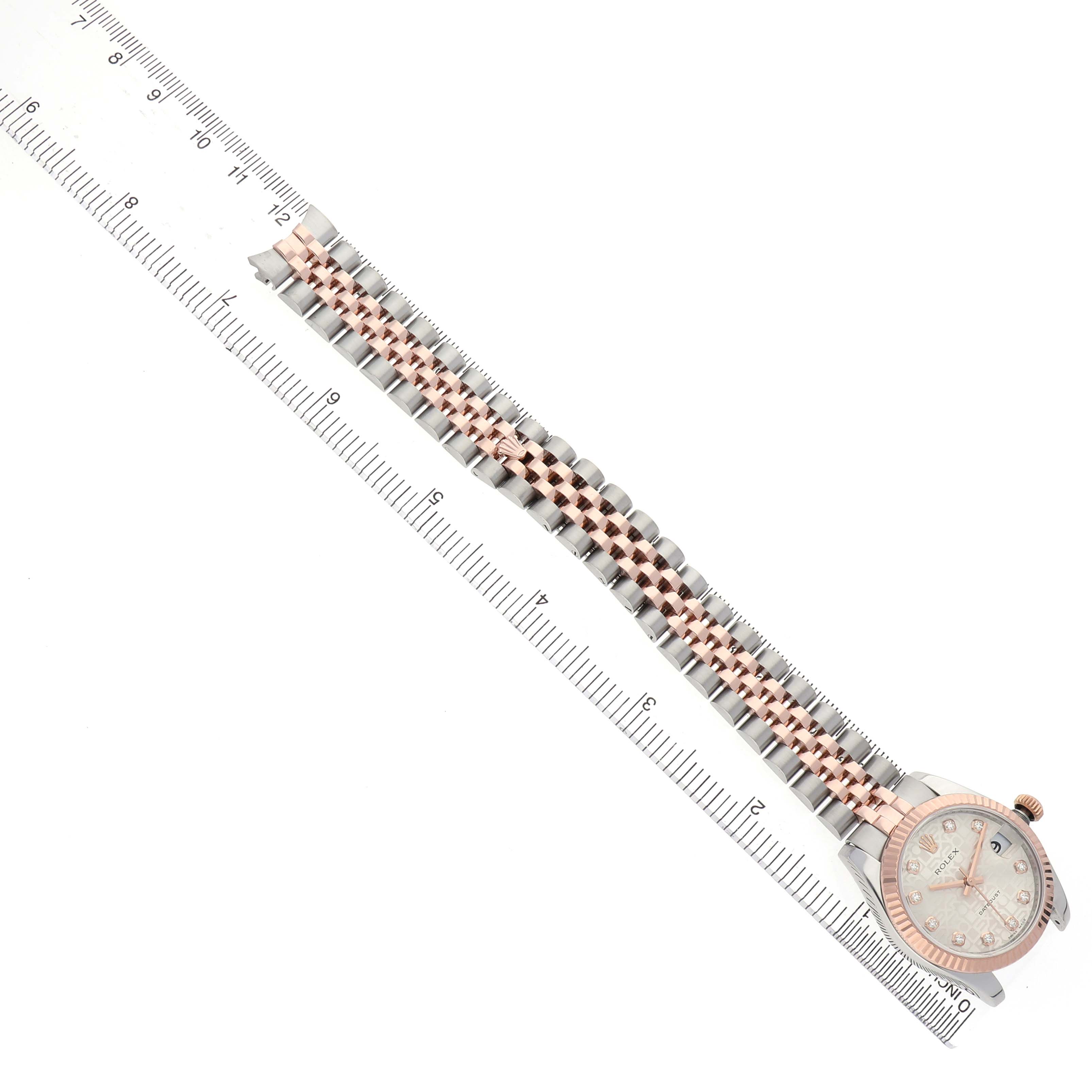 The Rolex Mid-Size 178271 Women's Stainless Steel Silver Dial watch is shown from a top-down angle, highlighting the dial and bracelet alongside a ruler for scale.