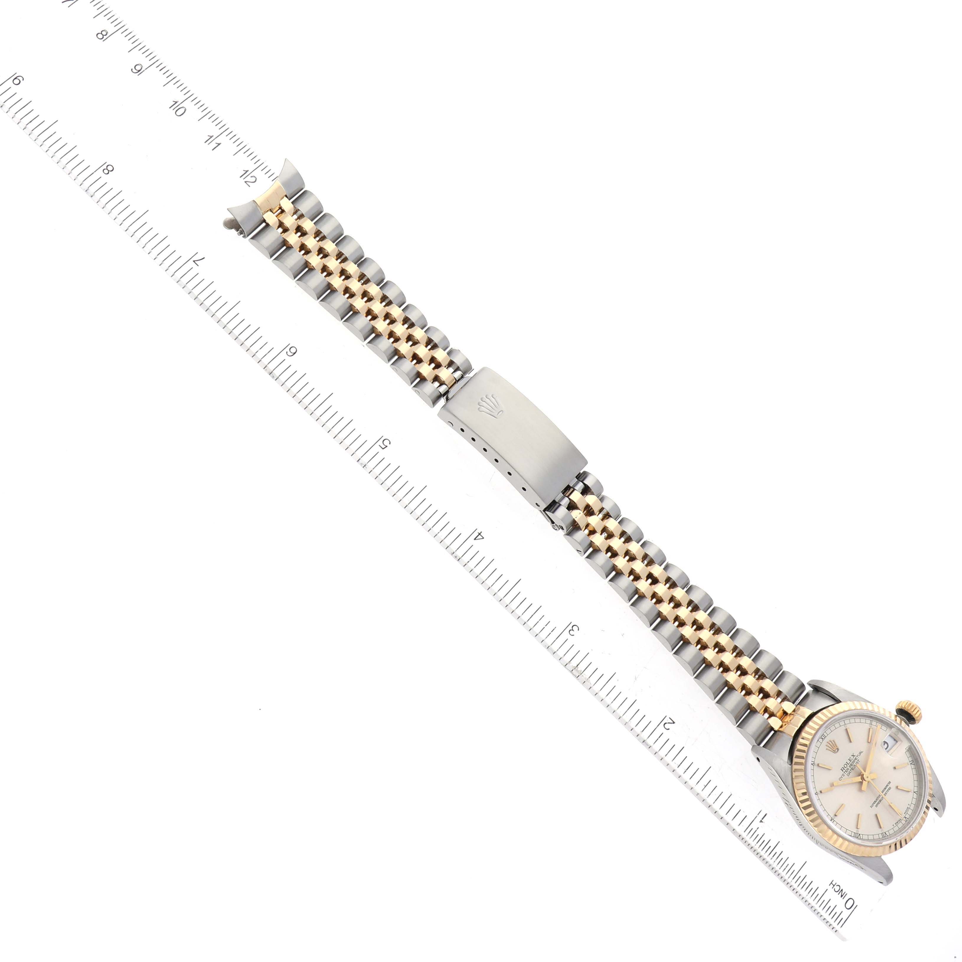 The image shows a top view of a Rolex Mid-Size 68273 Women's Steel and Gold (two tone) Silver Dial 68273 Women's Steel and Gold (two tone) Silver Dial watch, highlighting the band, clasp, and part of the watch face, with a ruler for scale.