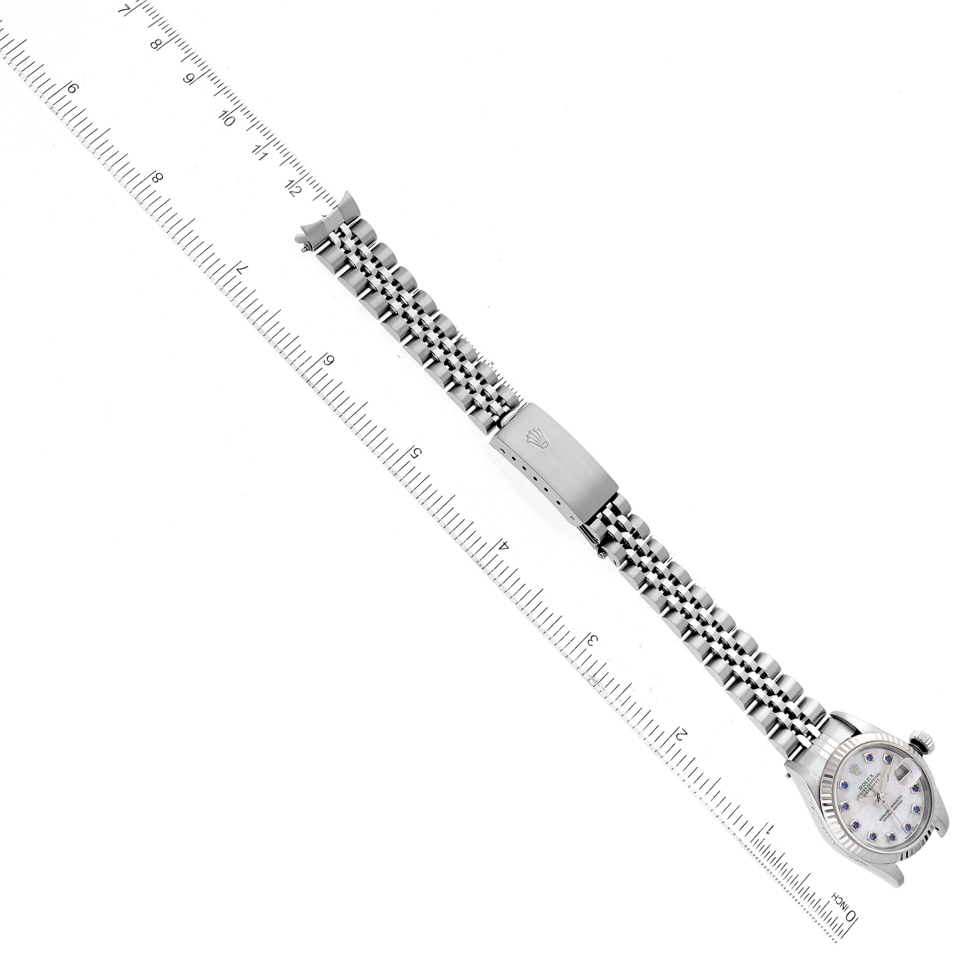 This image shows a top-down view of a Rolex Datejust 79174 Women
s Stainless Steel Mother of Pearl Dial 79174 Women
s Stainless Steel Mother of Pearl Dial watch, including its dial, bracelet, and clasp, alongside a measuring scale.