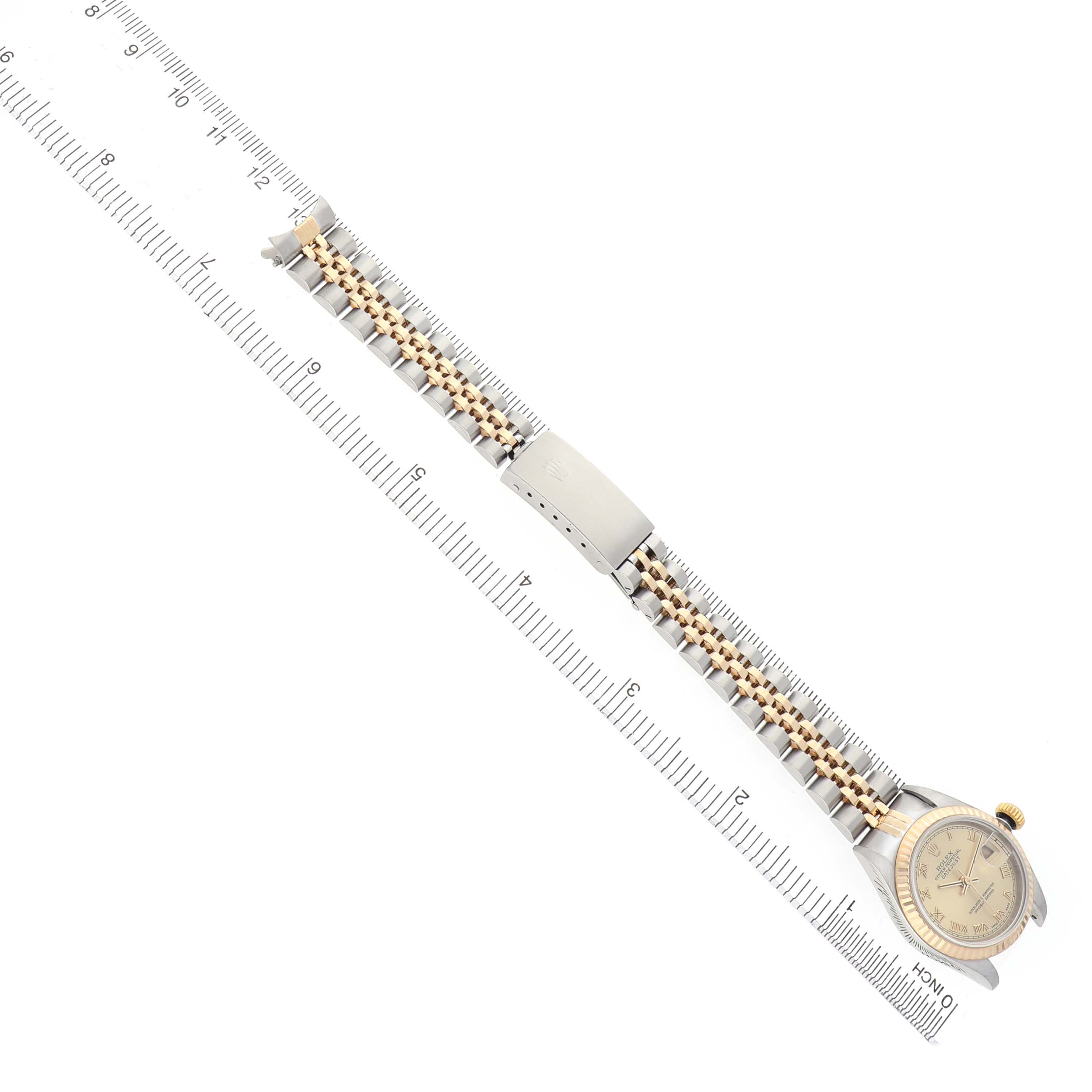 The Rolex Datejust 79173 Women's Stainless Steel Champagne Dial watch is shown from above, displaying its bracelet and clasp alongside a measuring scale.