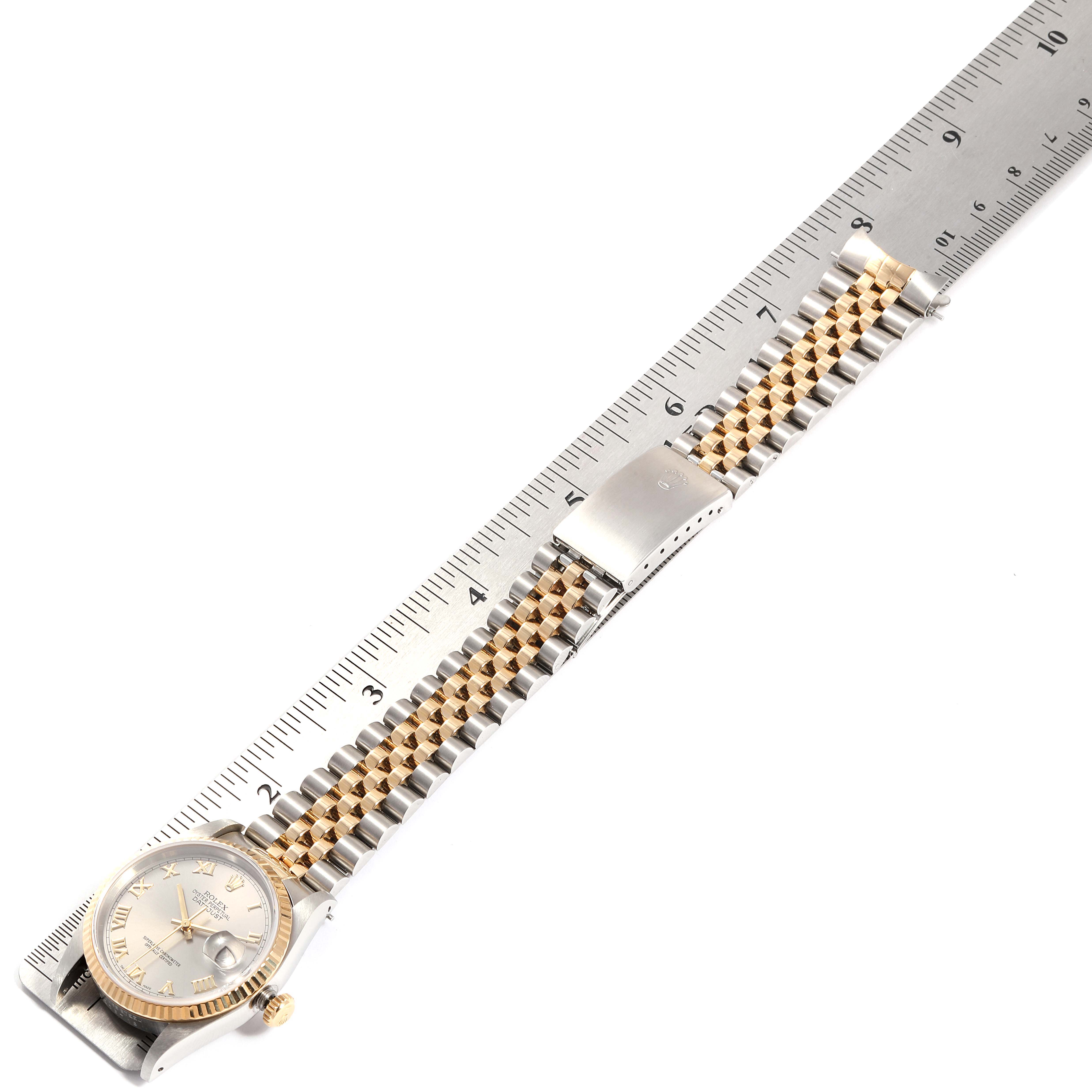 The Rolex Datejust 16233 Men's Steel and Gold (two tone) Grey Dial 16233 Men's Steel and Gold (two tone) Grey Dial watch is shown from a top-down angle, displaying its face, strap, and clasp, with a ruler underneath for scale.