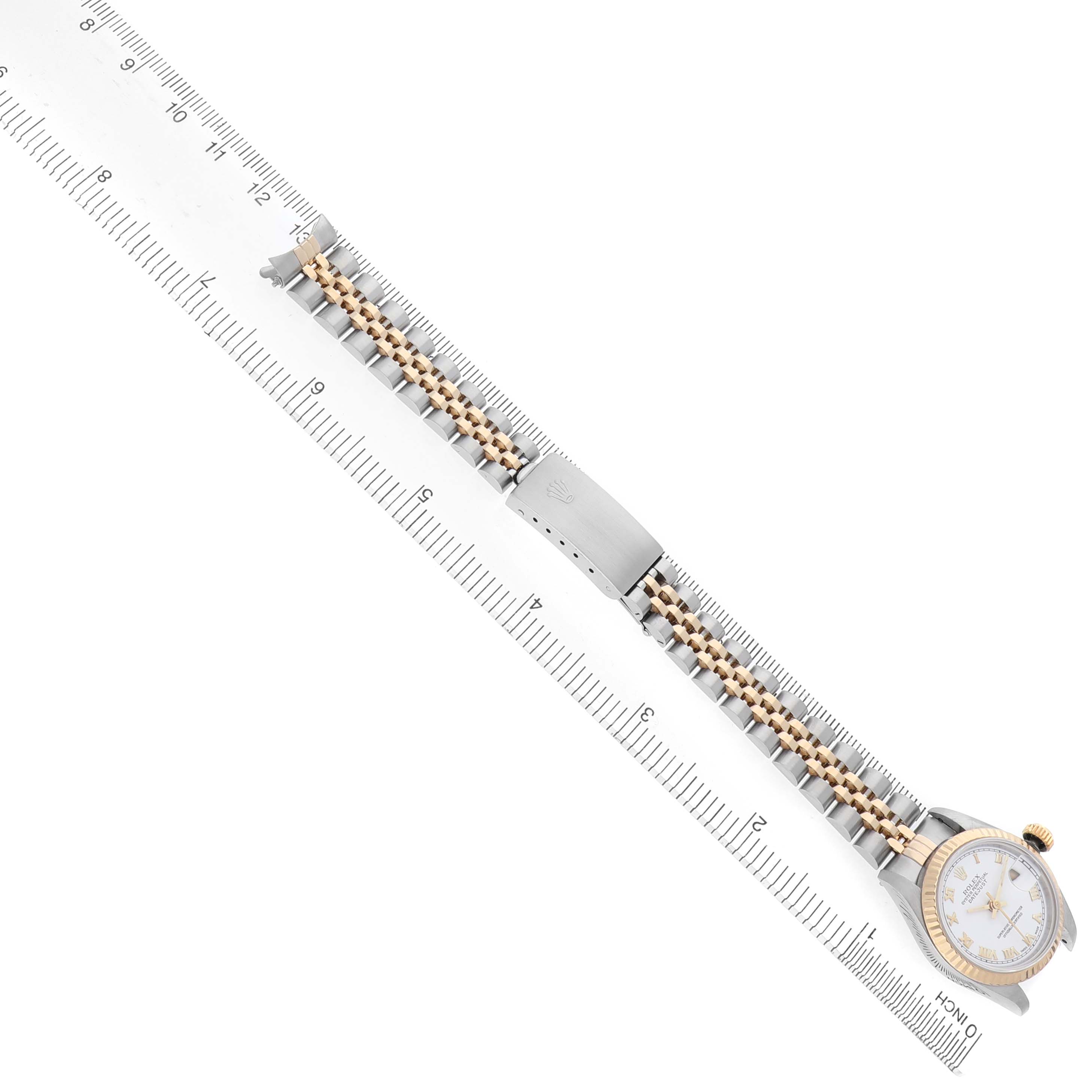 The Rolex Datejust 69173 Women's Steel and Gold (two tone) White Dial watch is shown diagonally with the full band extended, alongside a measuring ruler.